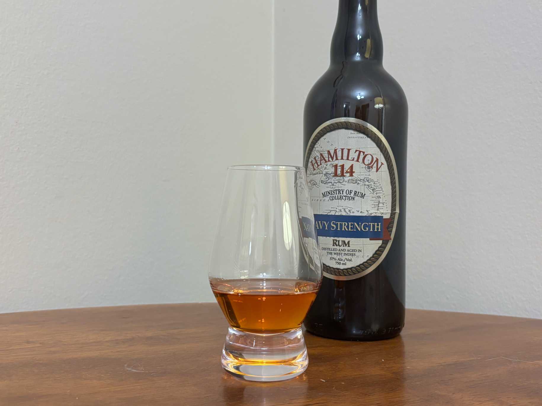 A bottle of Hamilton 114 Navy Strength next to a glass of rum