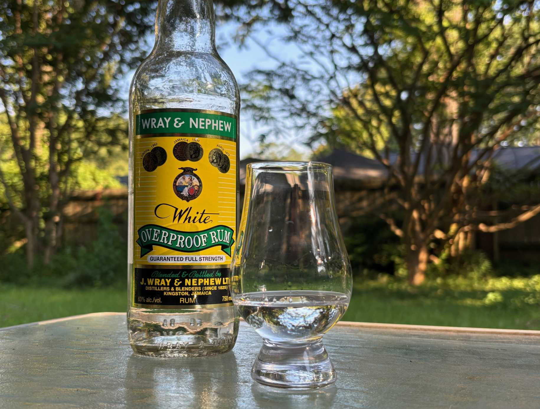 A bottle of Wray & Nephew White Overproof Rum next to a glass of rum