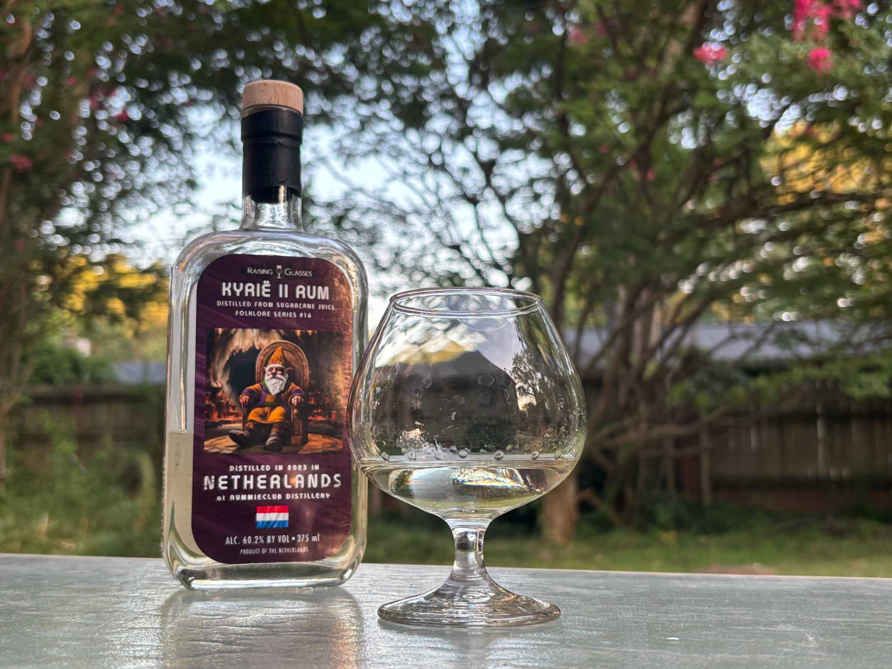 A bottle of Raising Glasses Kyrië II next to a glass of rum