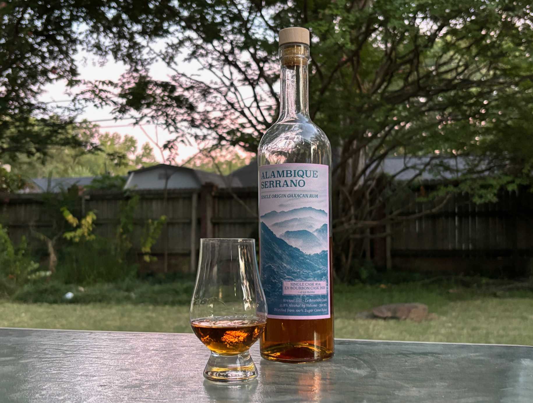 A bottle of Alambique Serrano Single Cask #14 2 year next to a glass of rum