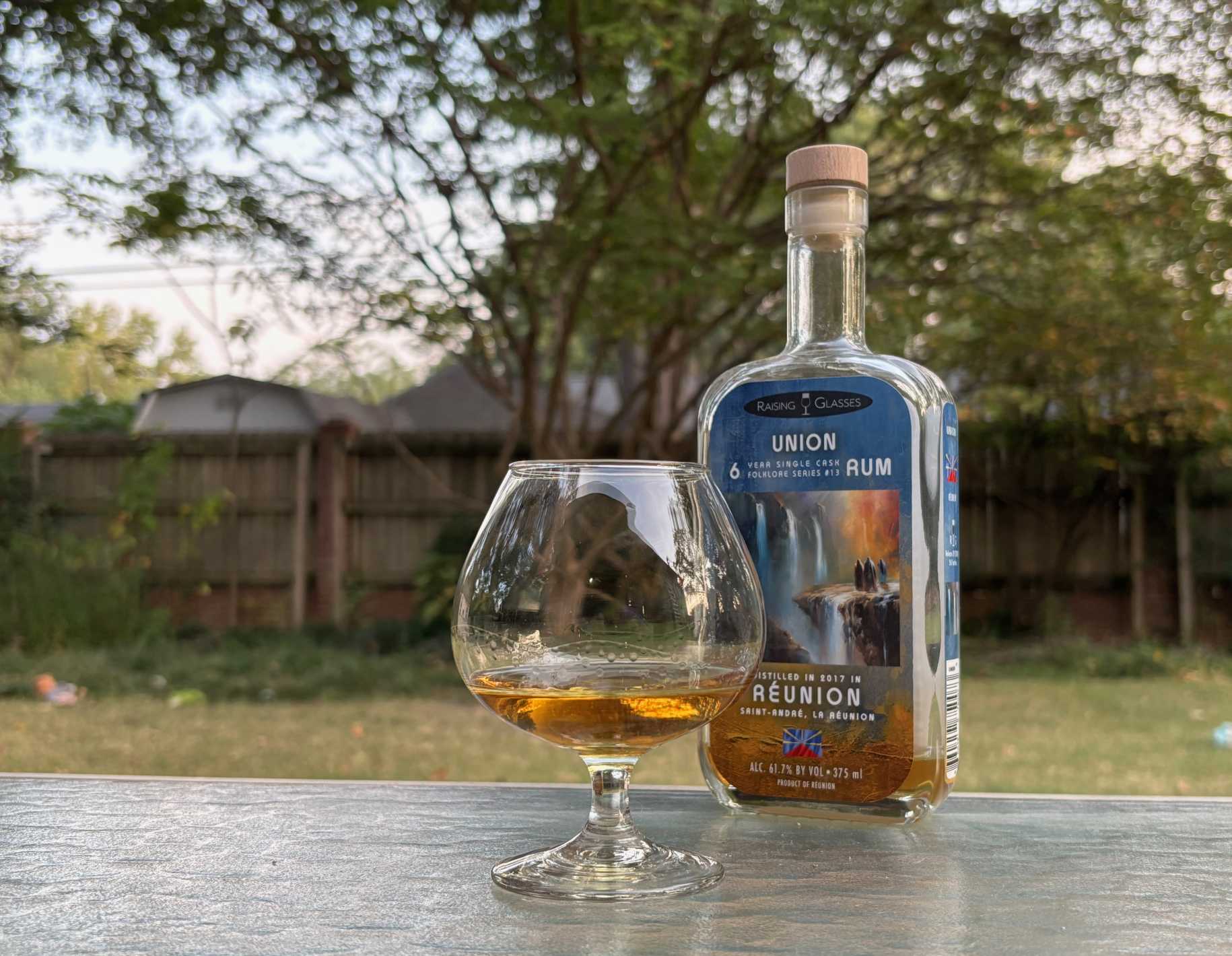 A bottle of Raising Glasses Union 6 year next to a glass of rum