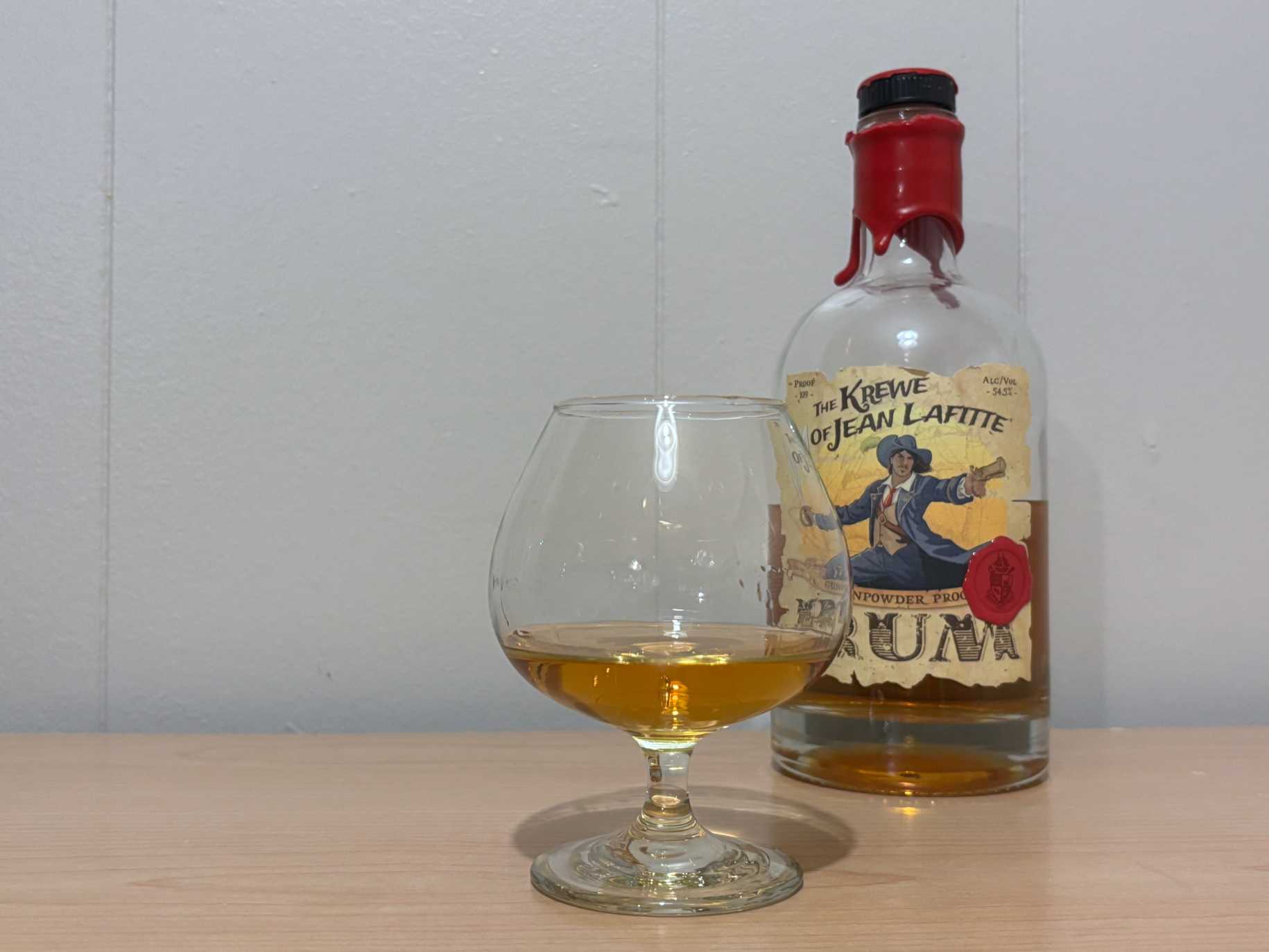 A bottle of Krewe of Jean Lafitte Gunpowder Proof next to a glass of rum