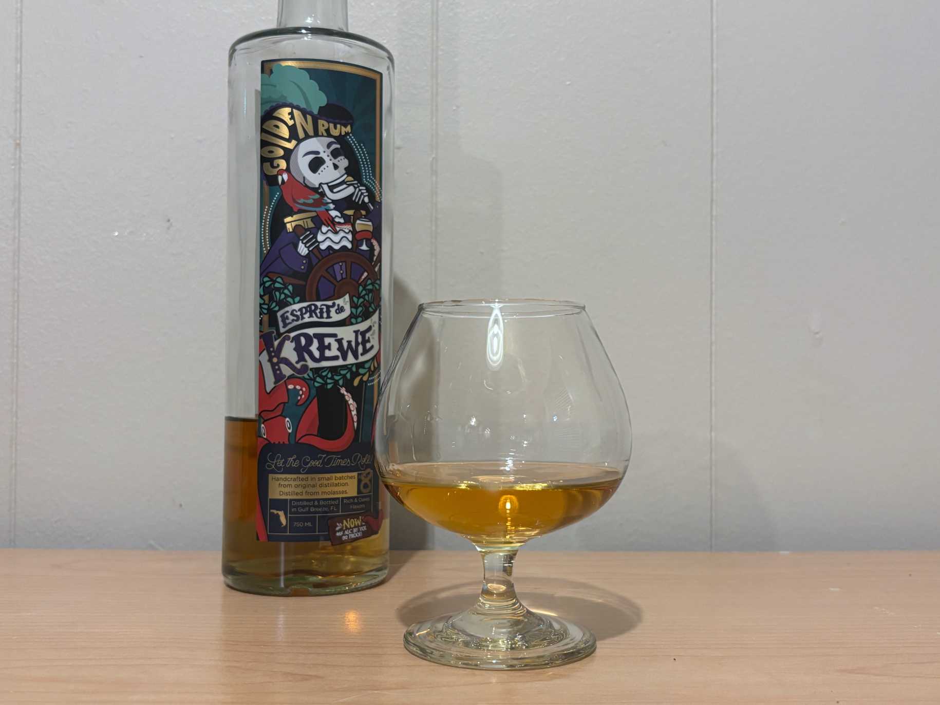 A bottle of Esprit de Krewe Golden Rum next to a glass of rum