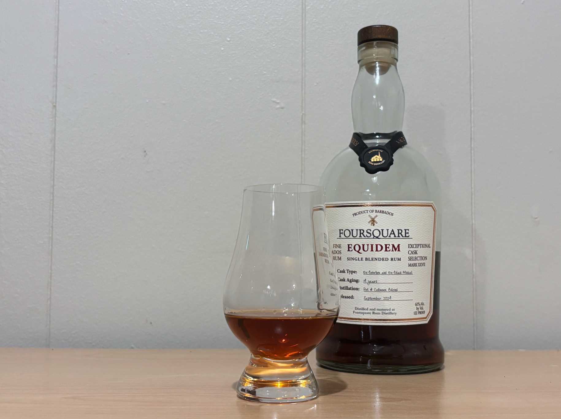 A bottle of Foursquare Equidem next to a glass of rum