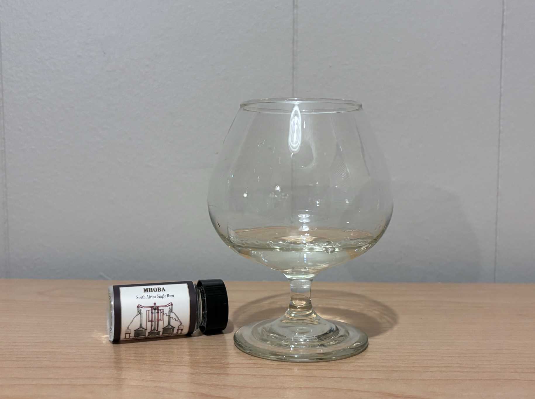 A bottle of Habitation Velier Mhoba Unaged next to a glass of rum