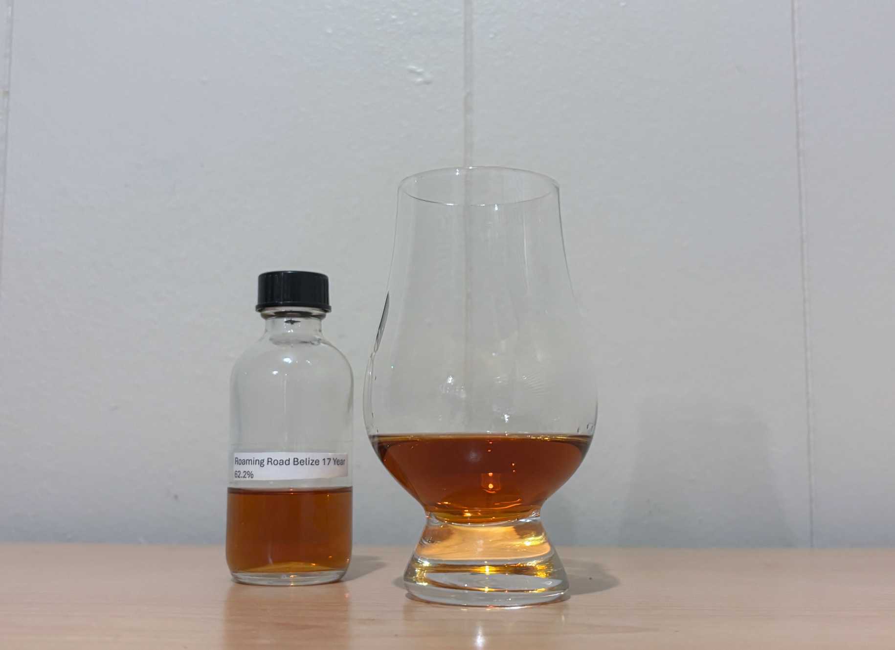 A bottle of Roaming Road Belize 17 year next to a glass of rum