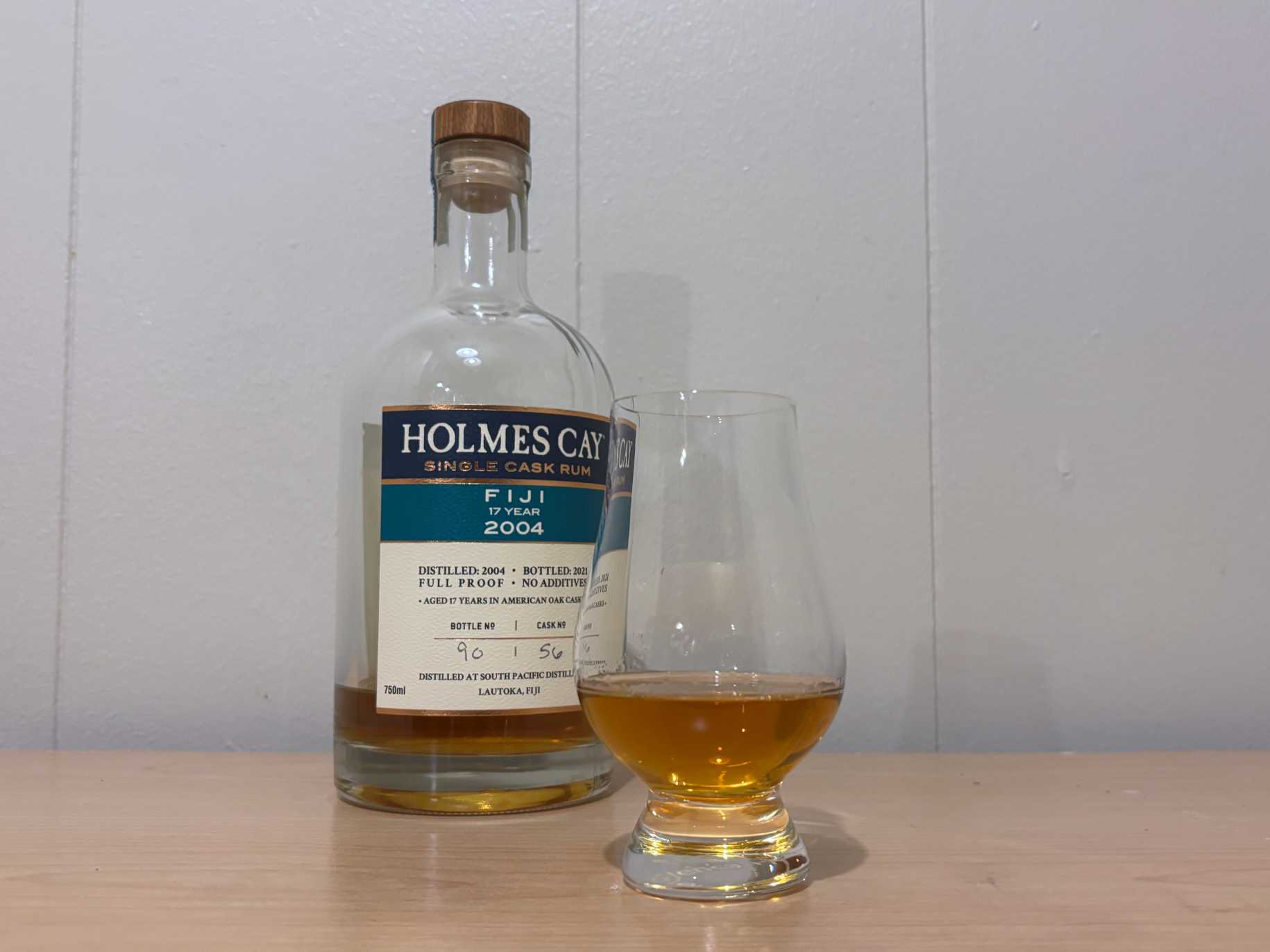 A bottle of Holmes Cay Fiji 2004 17 year next to a glass of rum