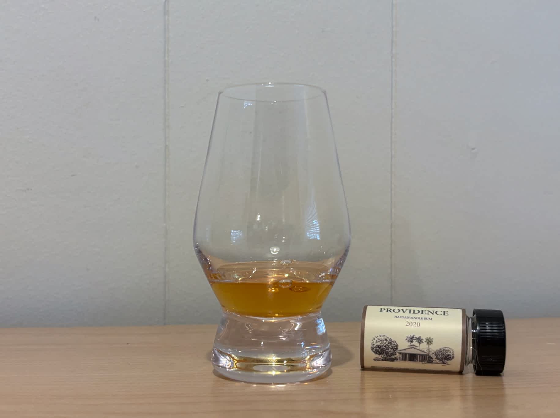 A bottle of Providence Haitian Single Rum 2020 3yr next to a glass of rum