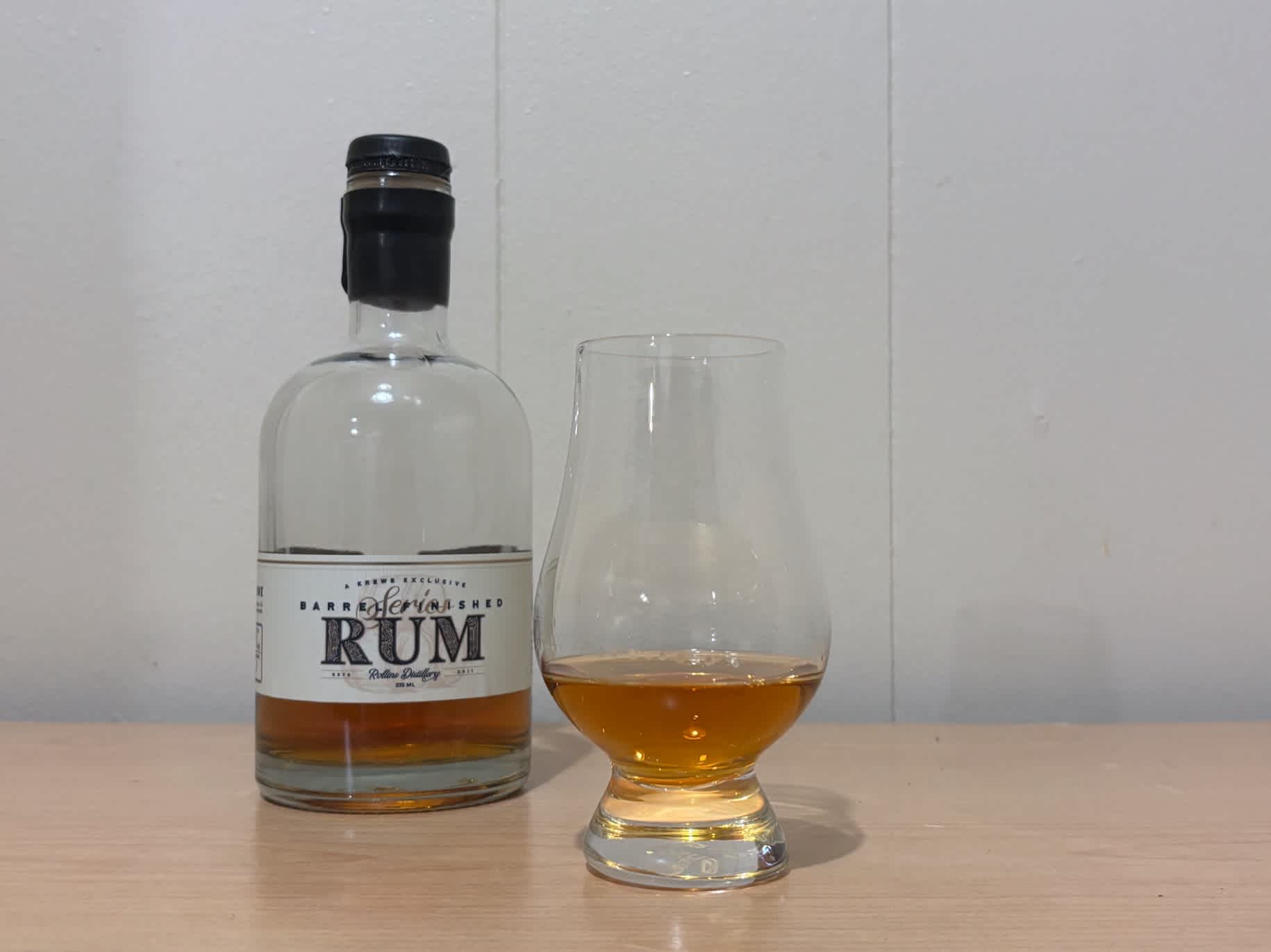 A bottle of Krewe Exclusive Barrel Finished Rum #3 next to a glass of rum