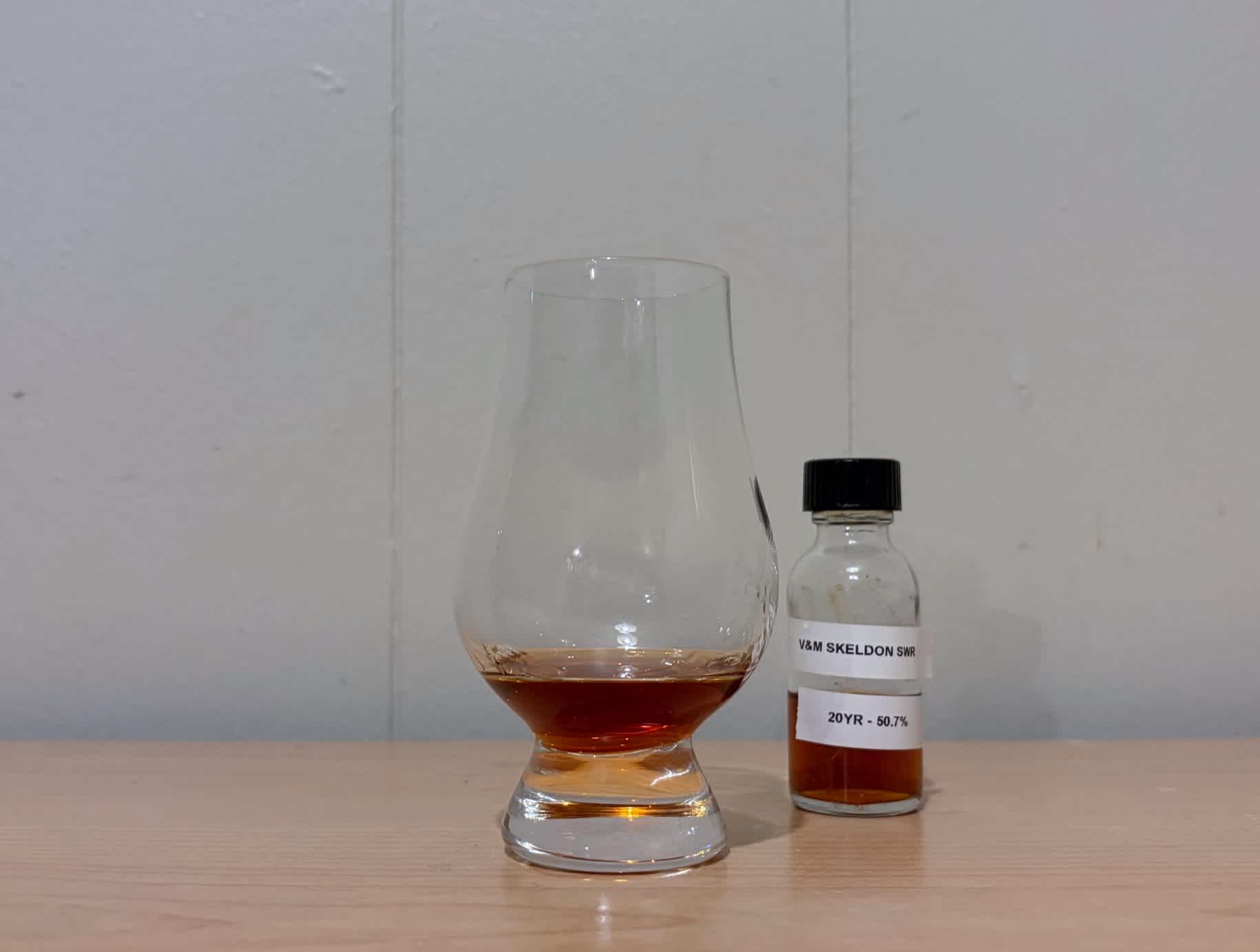 A bottle of Valinch & Mallet Skeldon SWR 20 Year next to a glass of rum