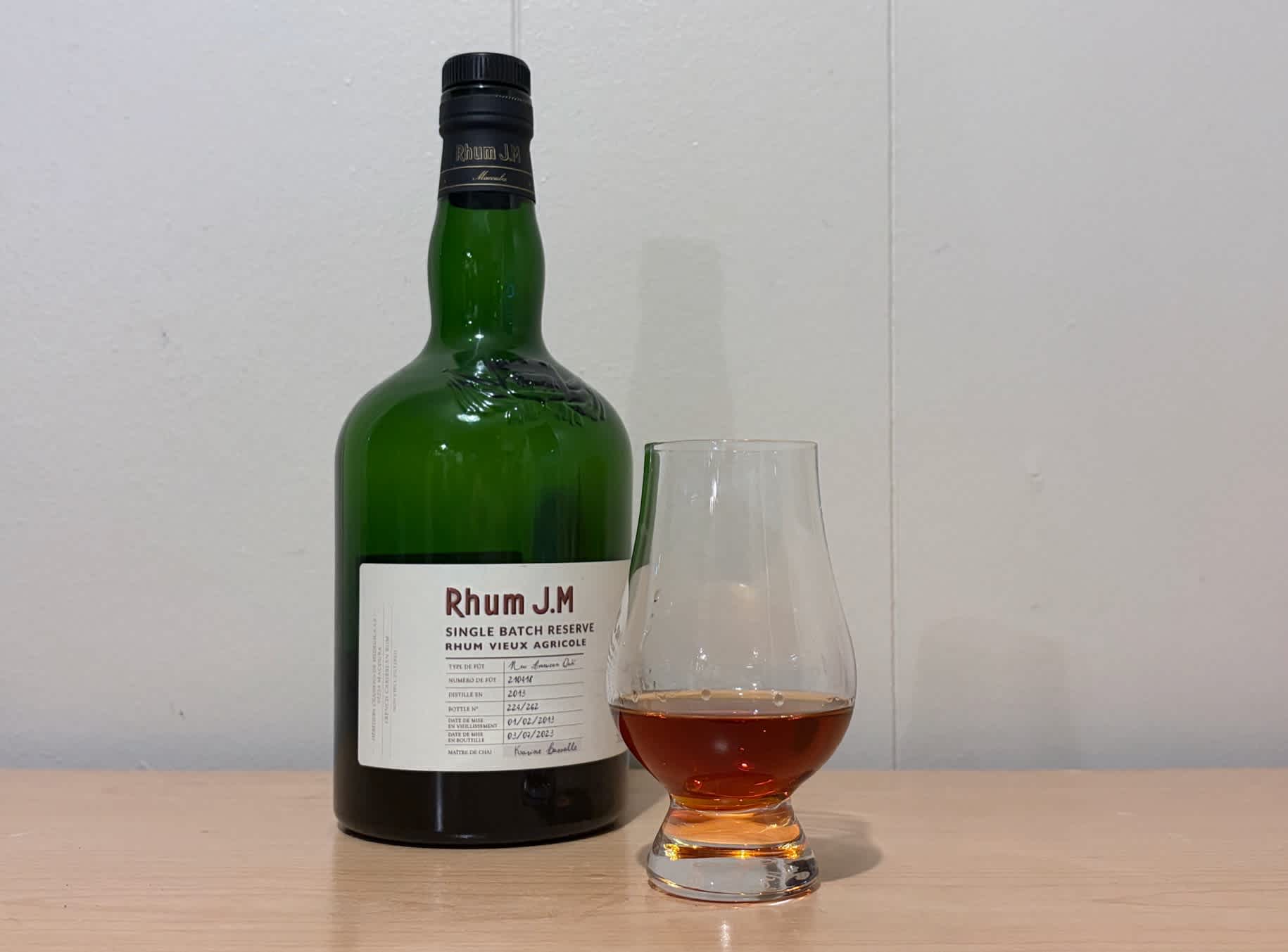 A bottle of Rhum JM Single Barrel Binny's 10yr next to a glass of rum