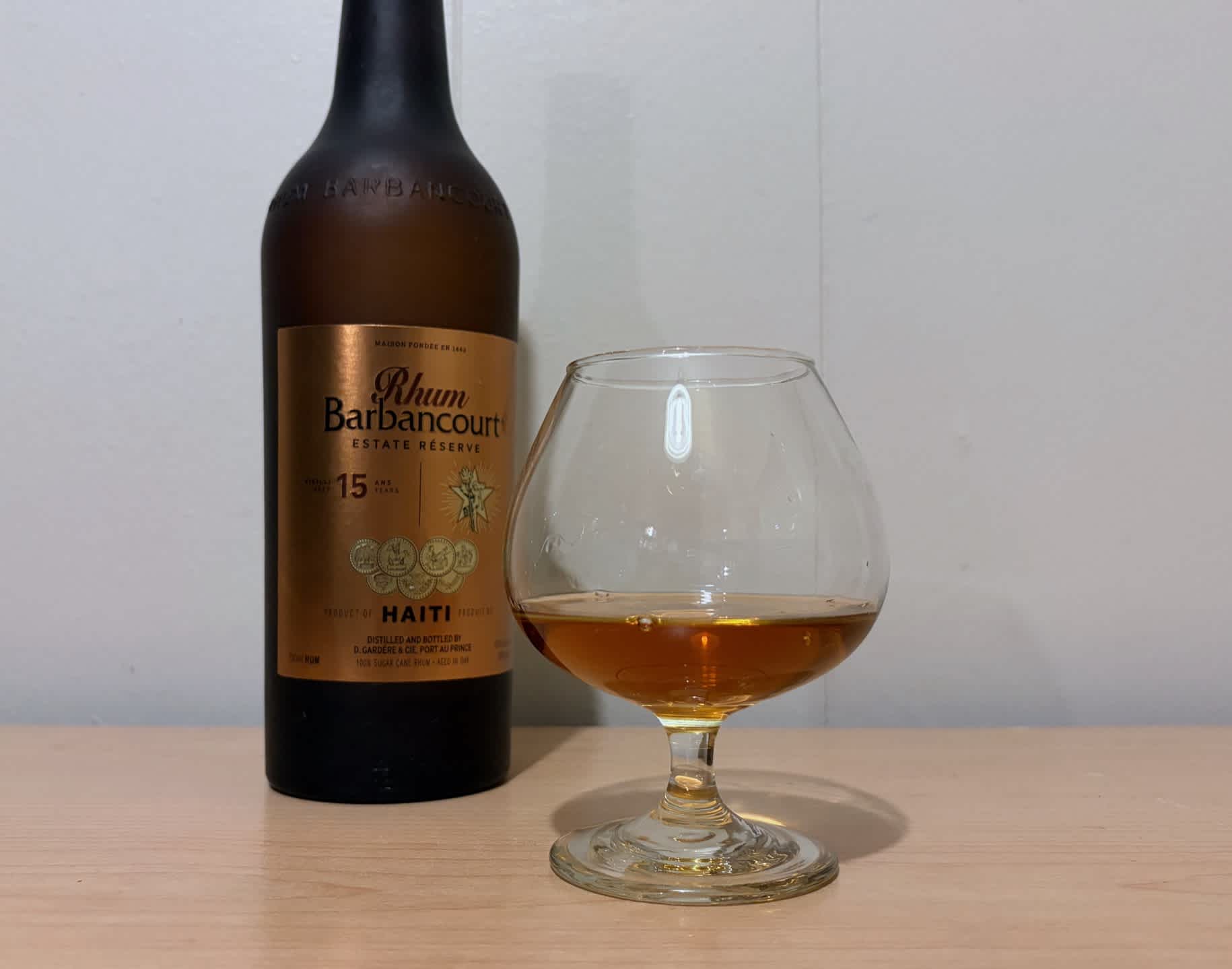 A bottle of Rhum Barbancourt 15 year next to a glass of rum