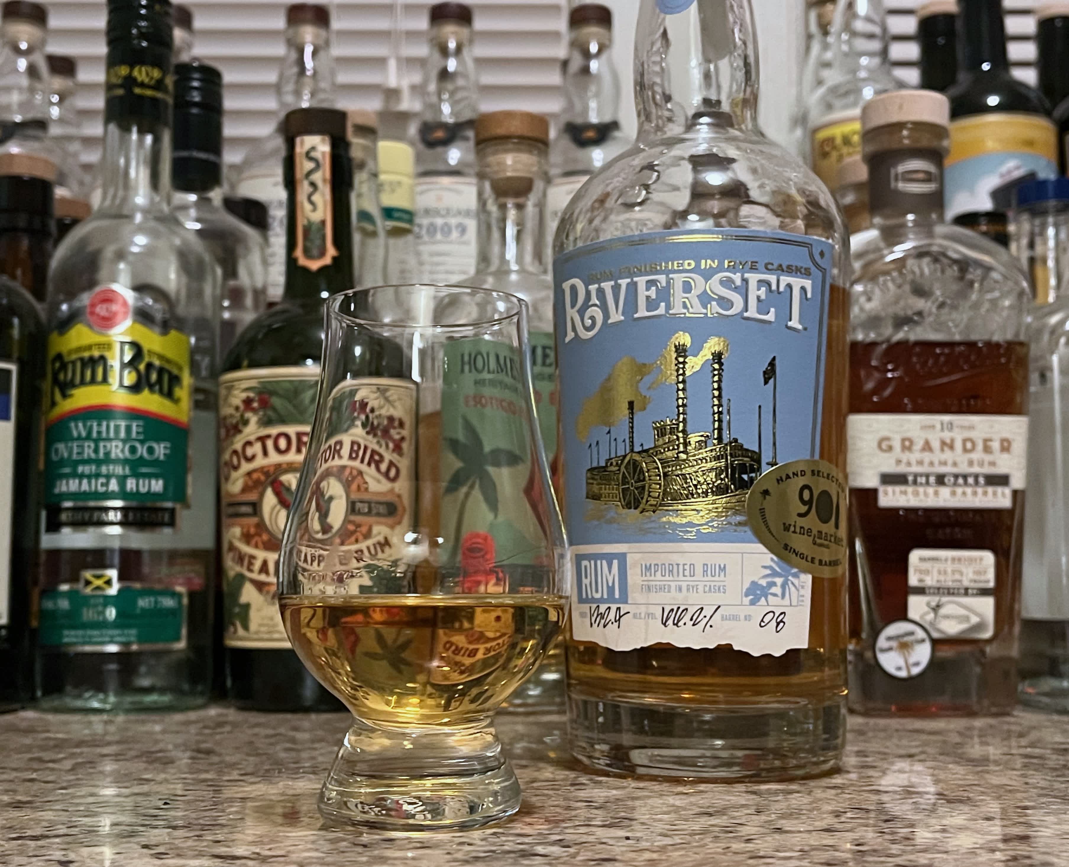 A bottle of Riverset Rum Barrel #08 next to a glencairn of rum