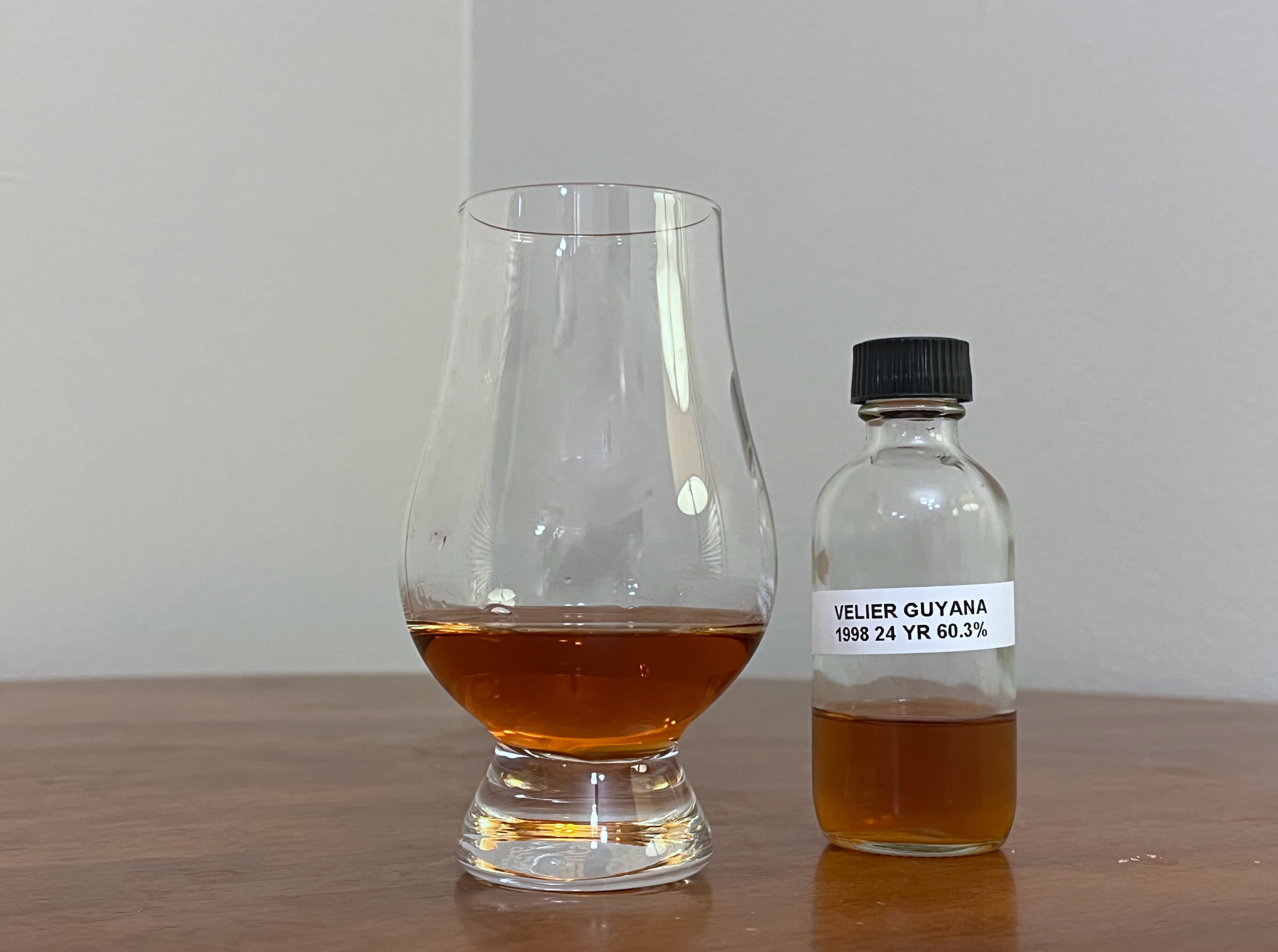 A bottle of La Maison & Velier Flag Series Guyana next to a glass of rum on a tabletop