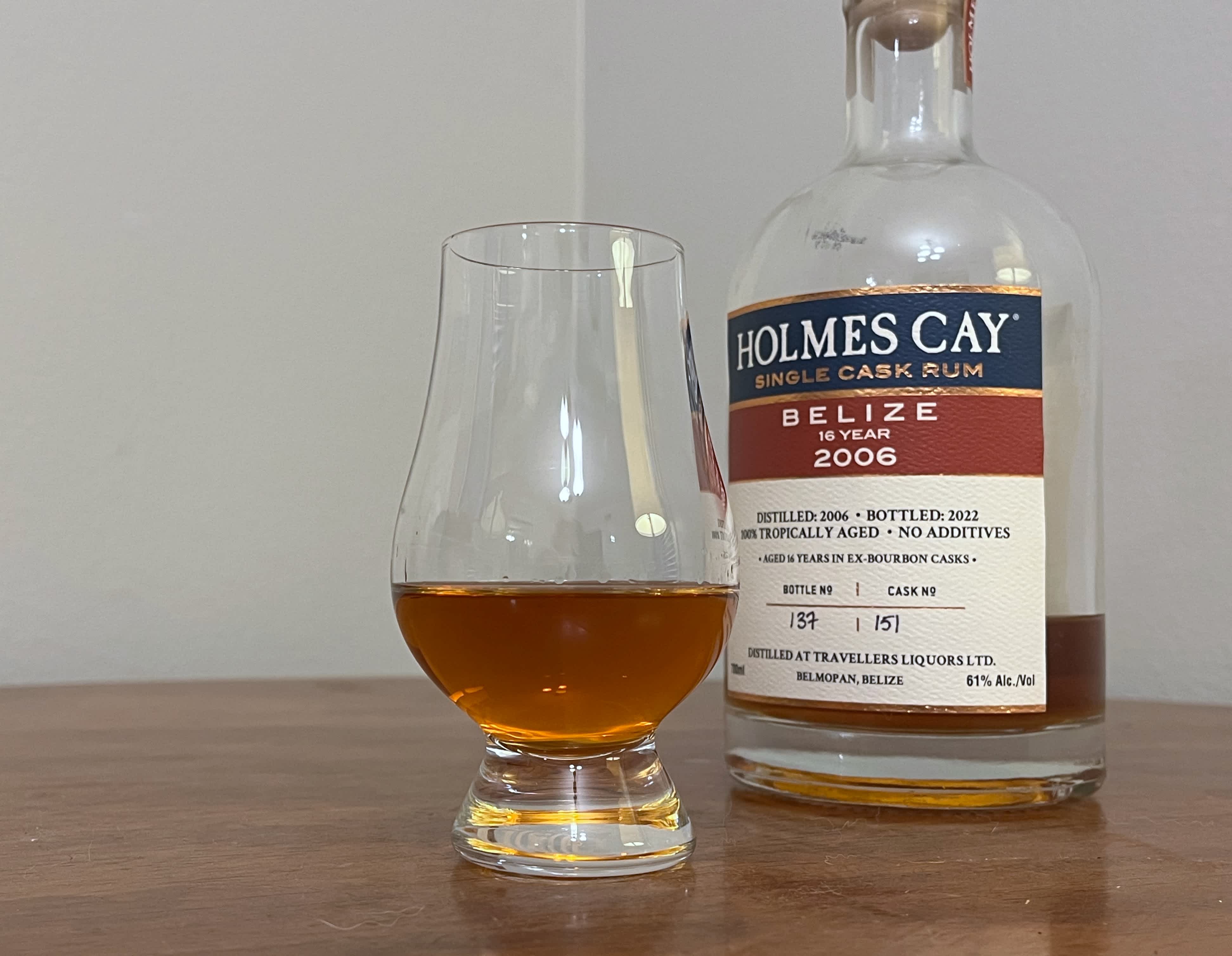 Bottle of Holmes Cay Belize 2006 next to a glencairn of rum on a table