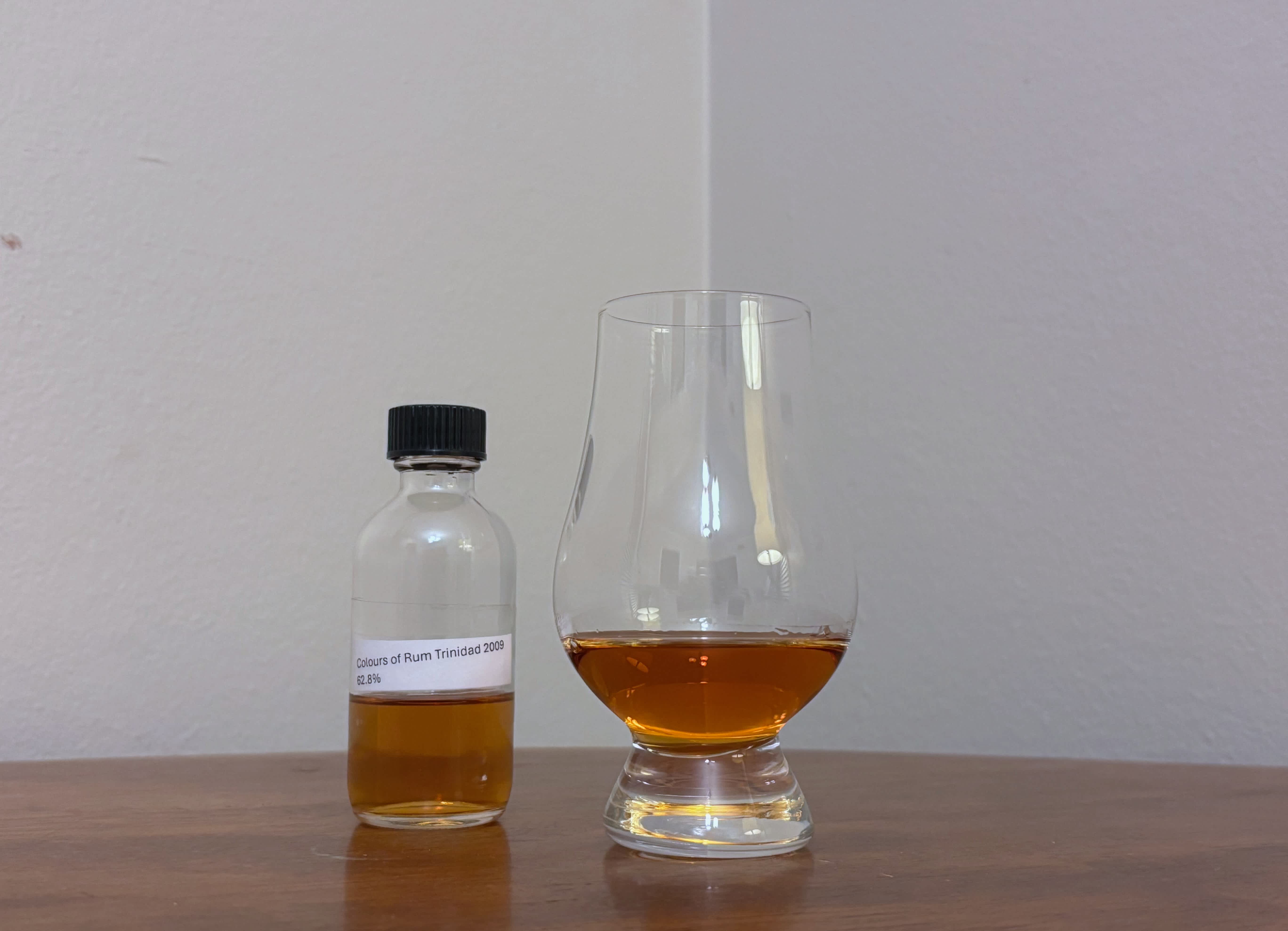 A bottle of Colours of Rum Trinidad 2009 next to a glass of rum
