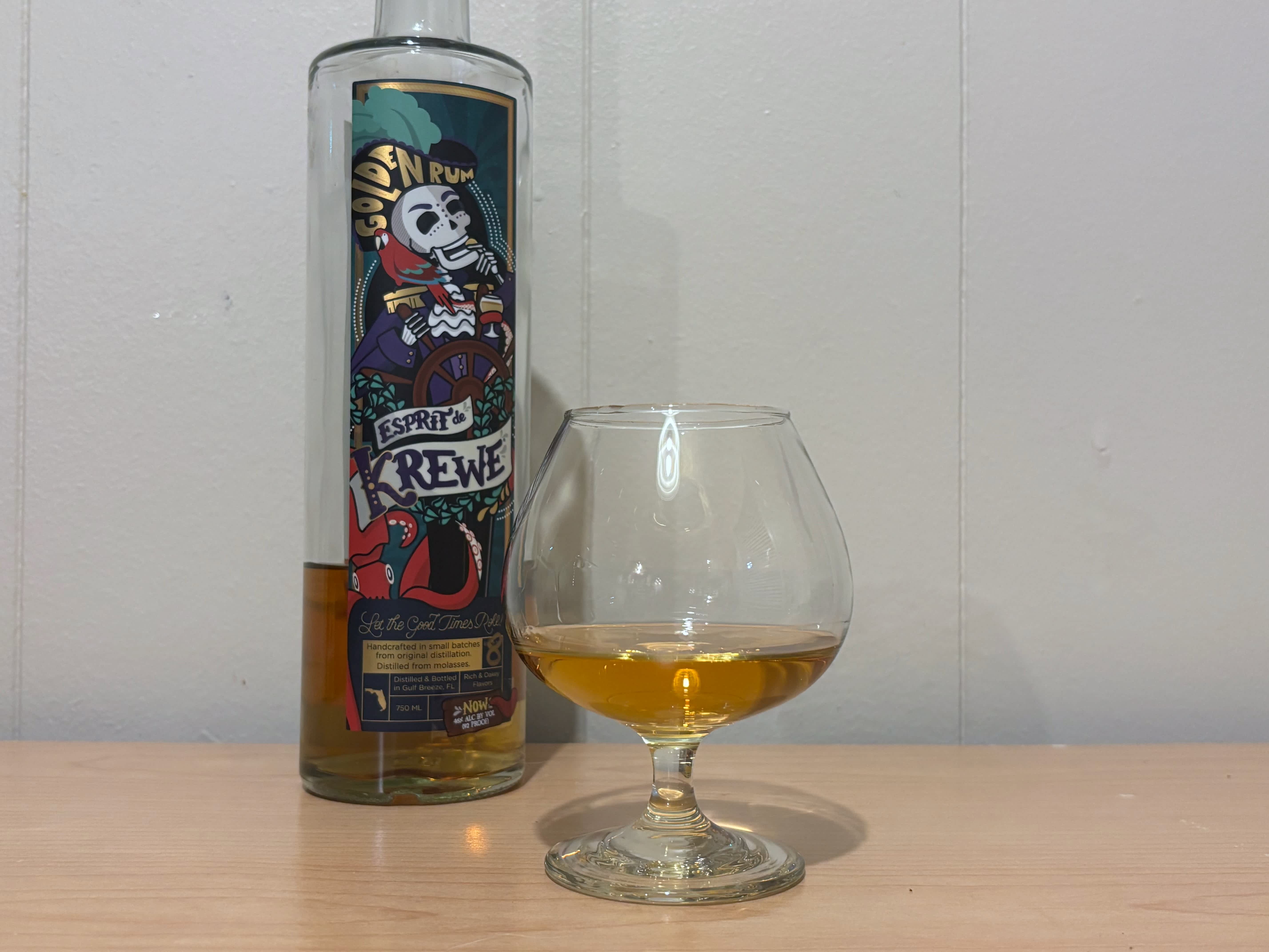 A bottle of Esprit de Krewe Golden Rum next to a glass of rum