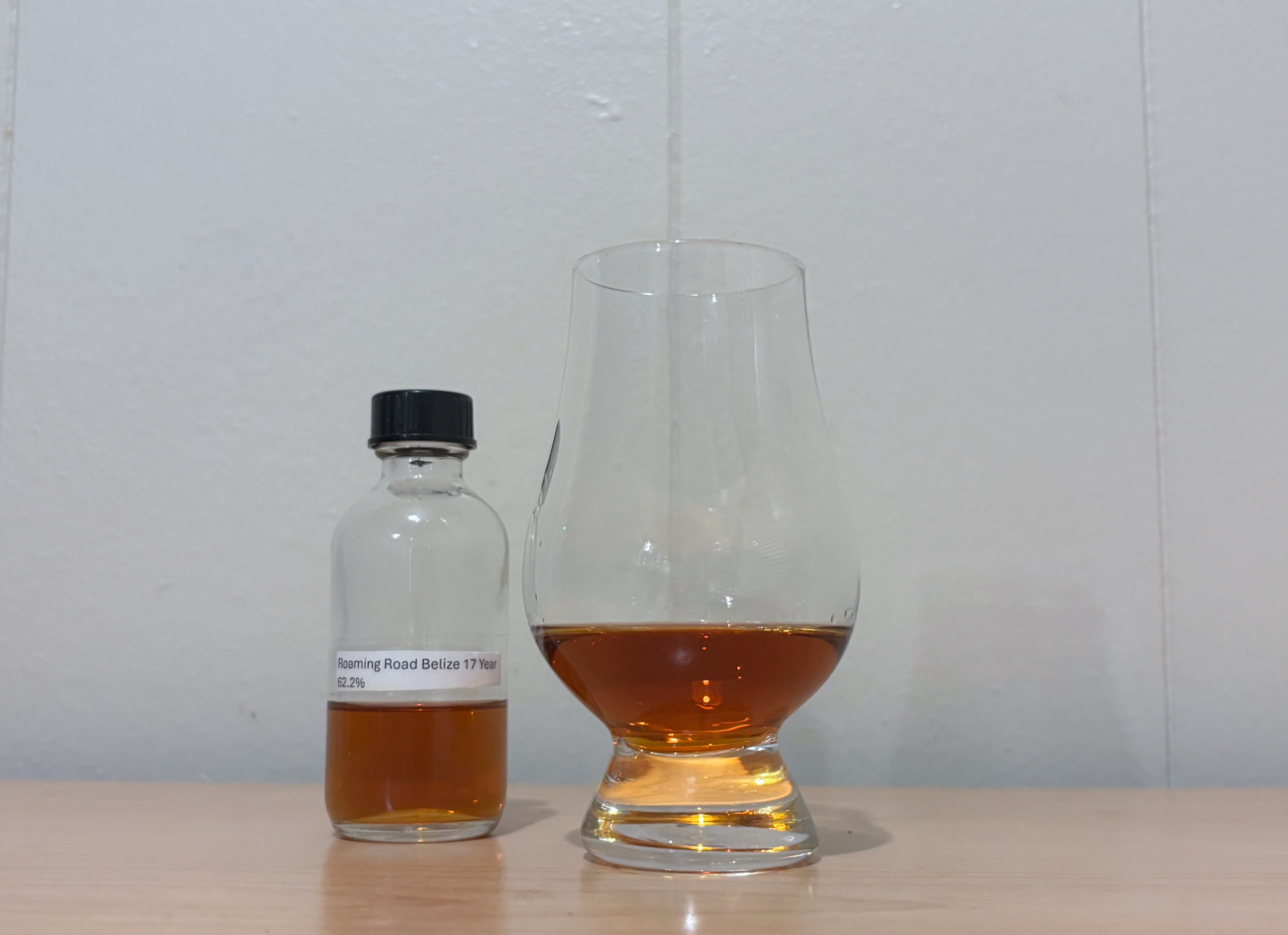 A bottle of Roaming Road Belize 17 year next to a glass of rum