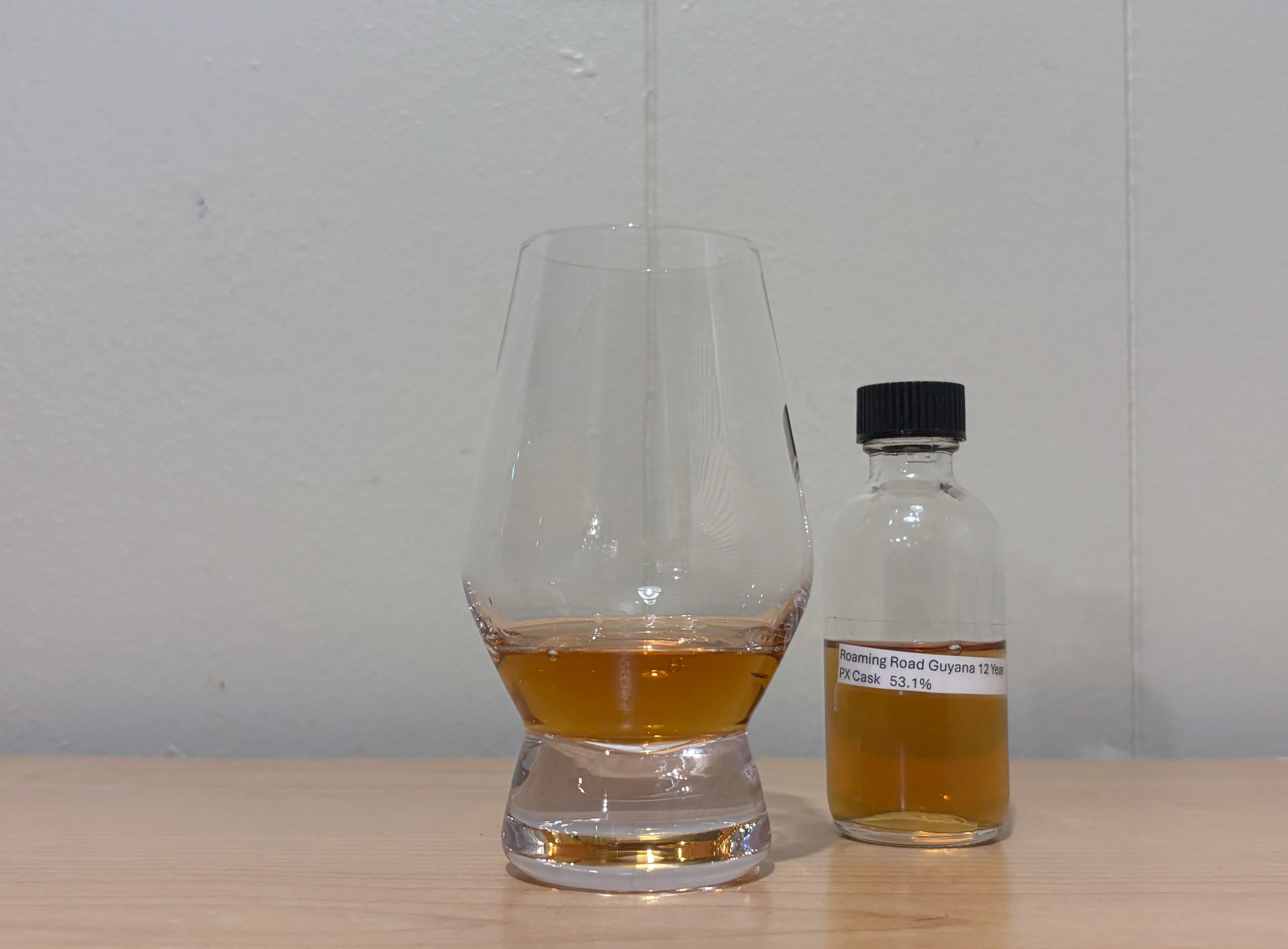 A bottle of Roaming Road Guyana 12 year next to a glass of rum