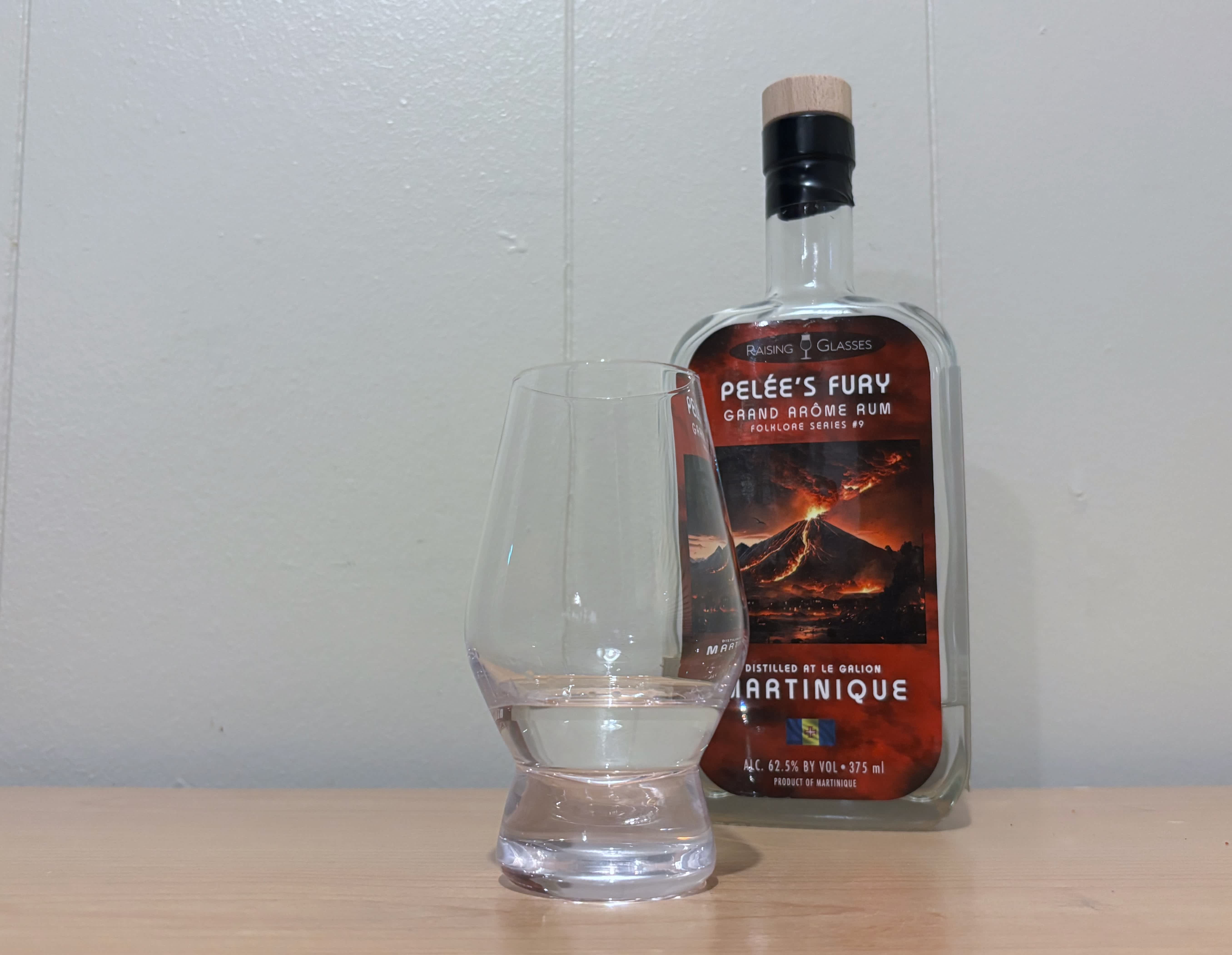 A bottle of Raising Glasses Pelee's Fury next to a glass of rum