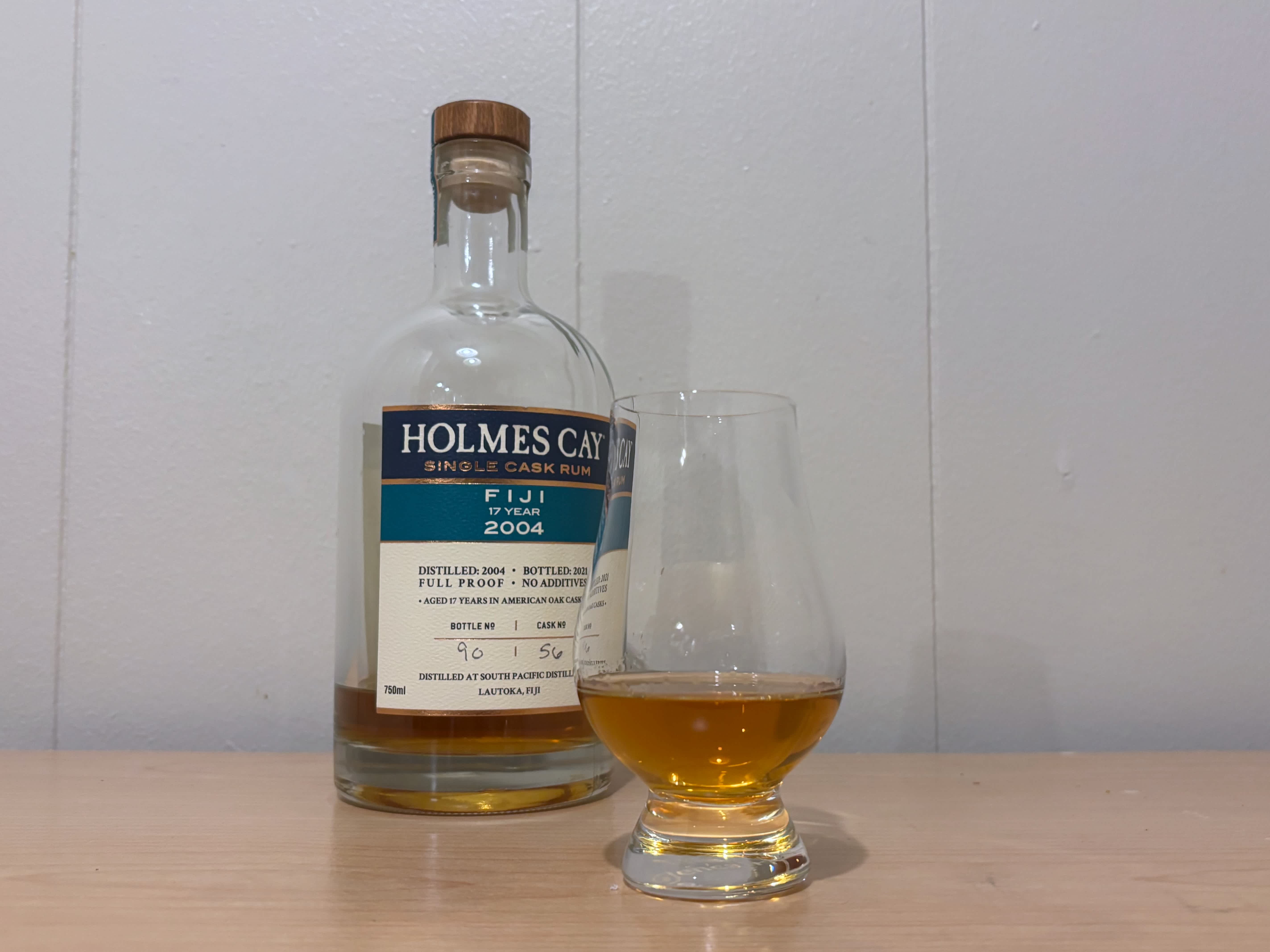 A bottle of Holmes Cay Fiji 2004 17 year next to a glass of rum