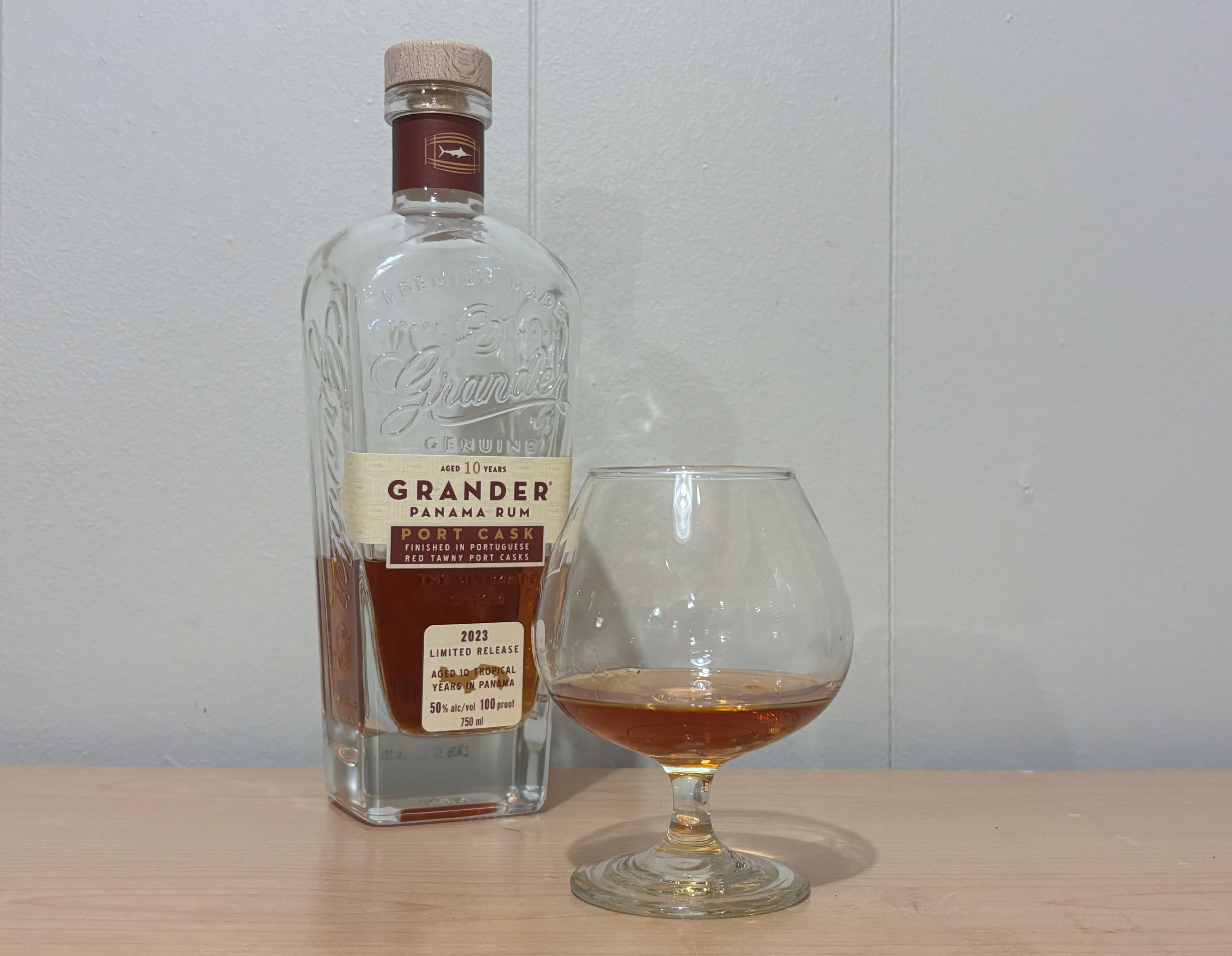A bottle of Grander Port Cask Finish 10 year next to a glass of rum