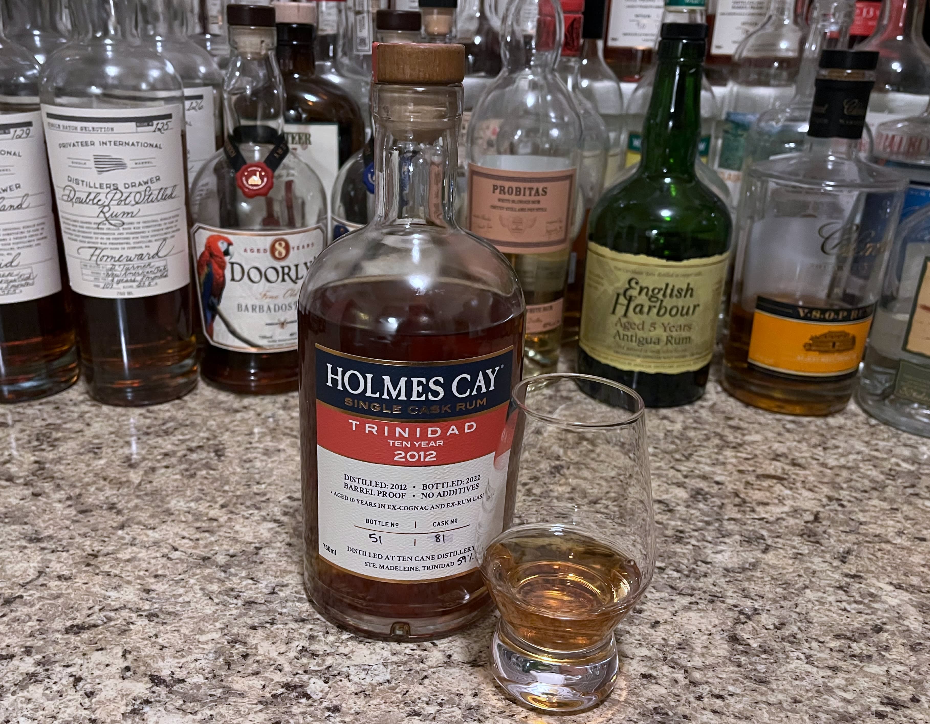 Bottle of Holmes Cay Trinidad 2012 sitting next to a rum-filled glencairn