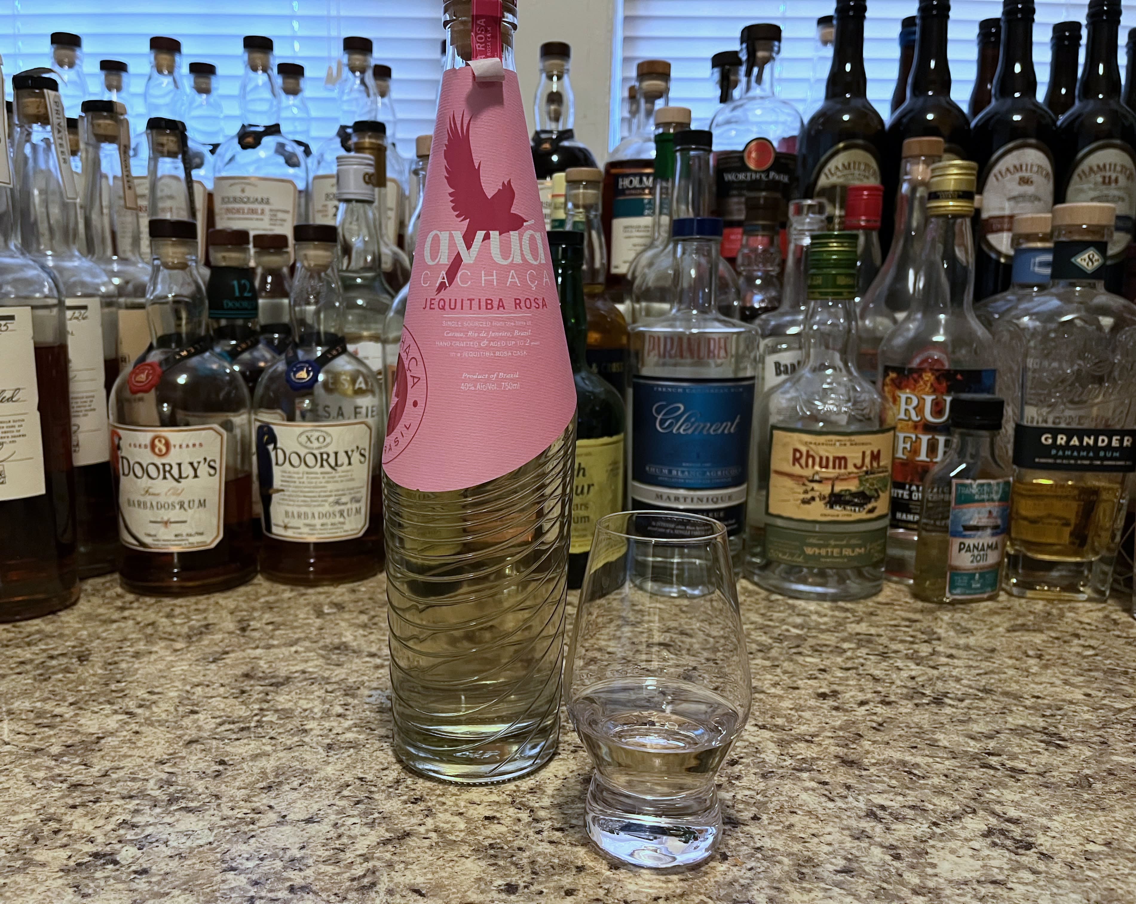 A bottle of Avuá Jequitiba Rosa next to a glencairn of cachaça on a kitchen counter