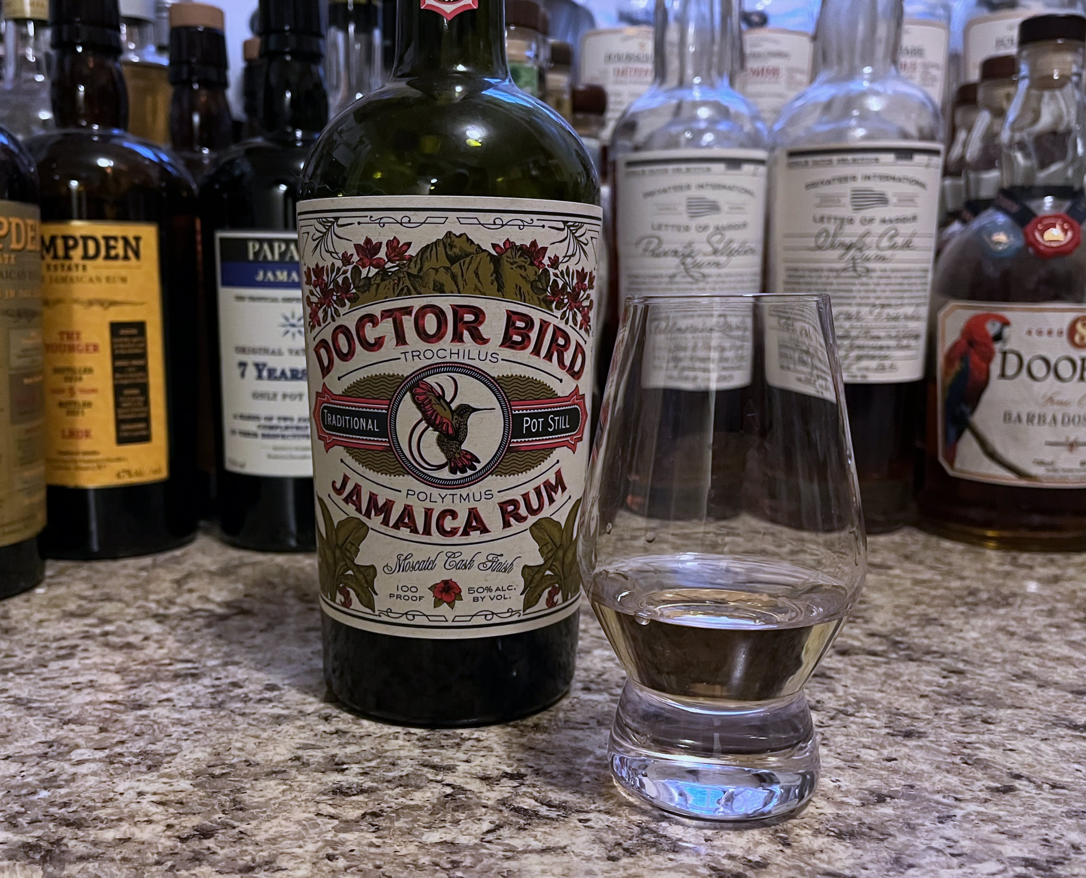 A bottle of Doctor Bird year next to a glencairn of rum on a kitchen counter