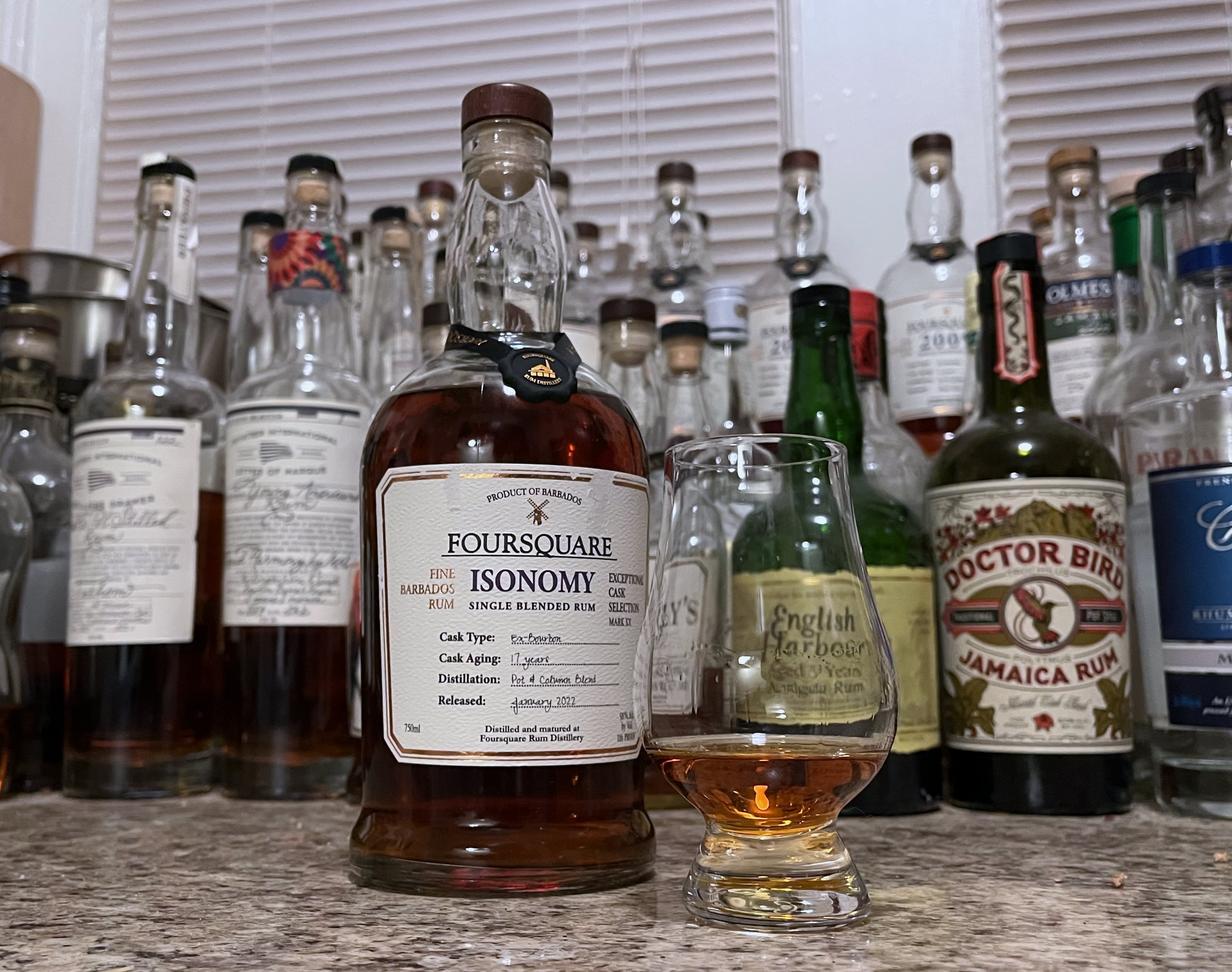 A bottle of Foursquare Isonomy next to a glencairn of rum