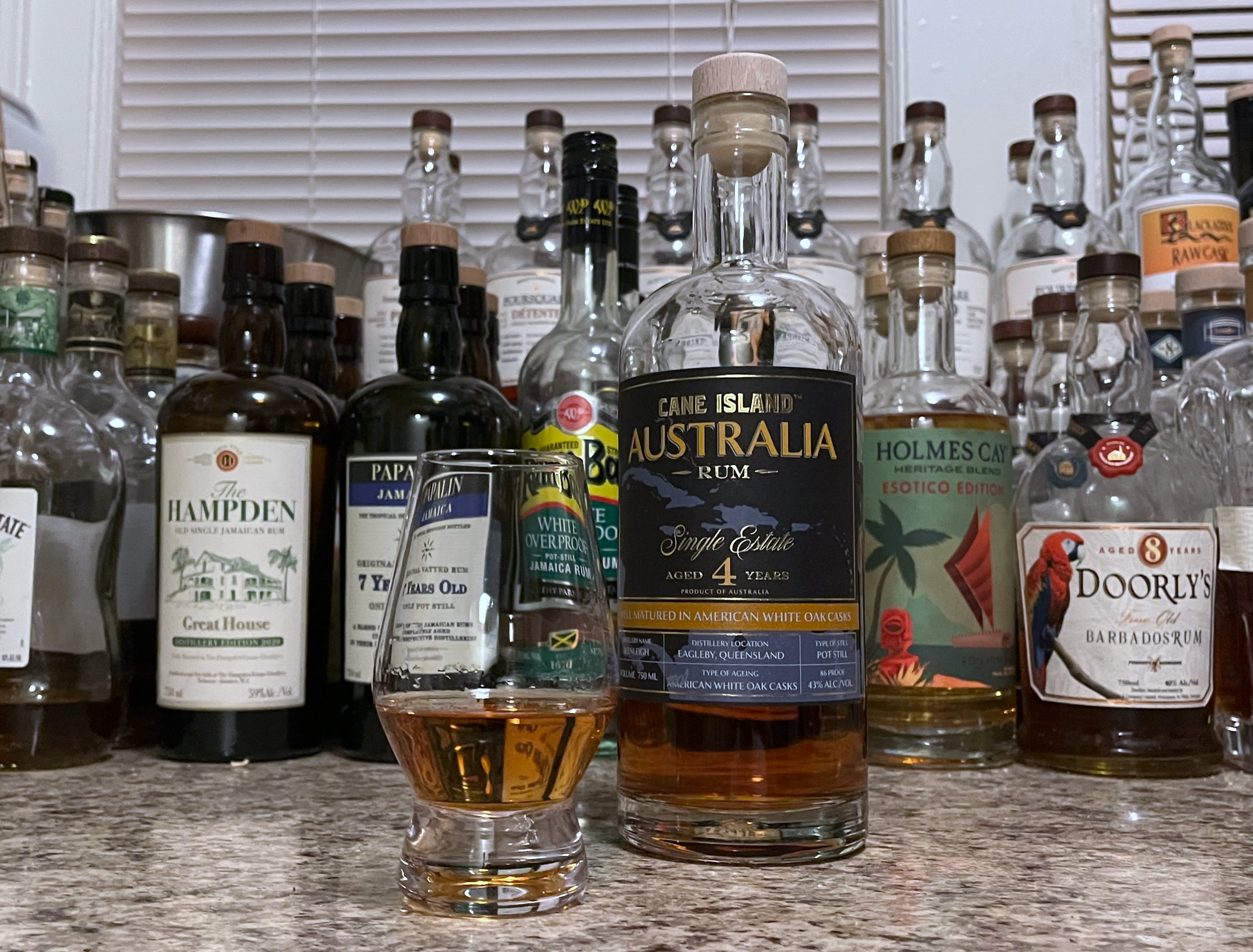 A bottle of Cane Island Australia next to a glencairn of rum on a kitchen counter