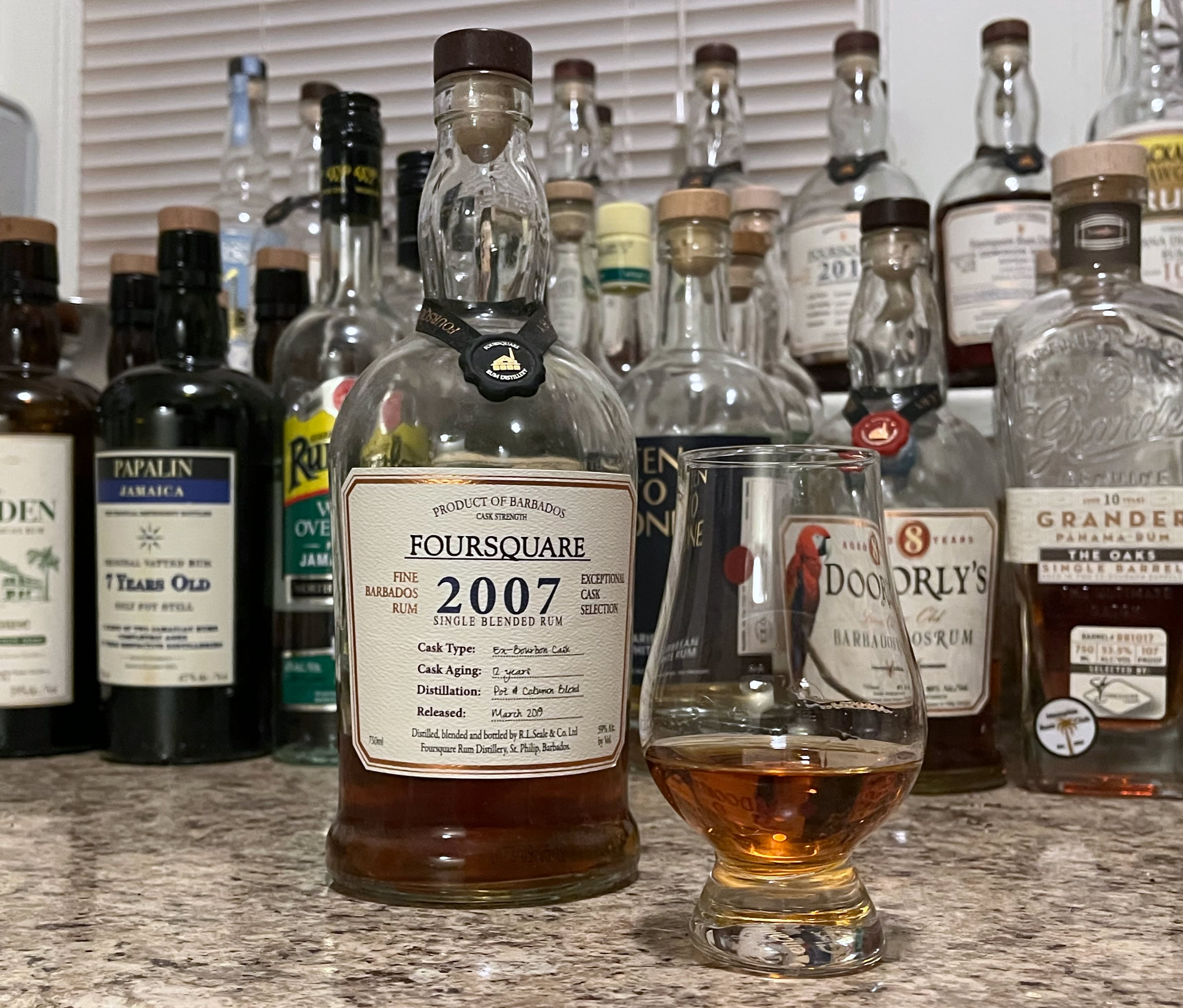 A bottle of Foursquare 2007 next to a glencairn of rum on a kitchen counter