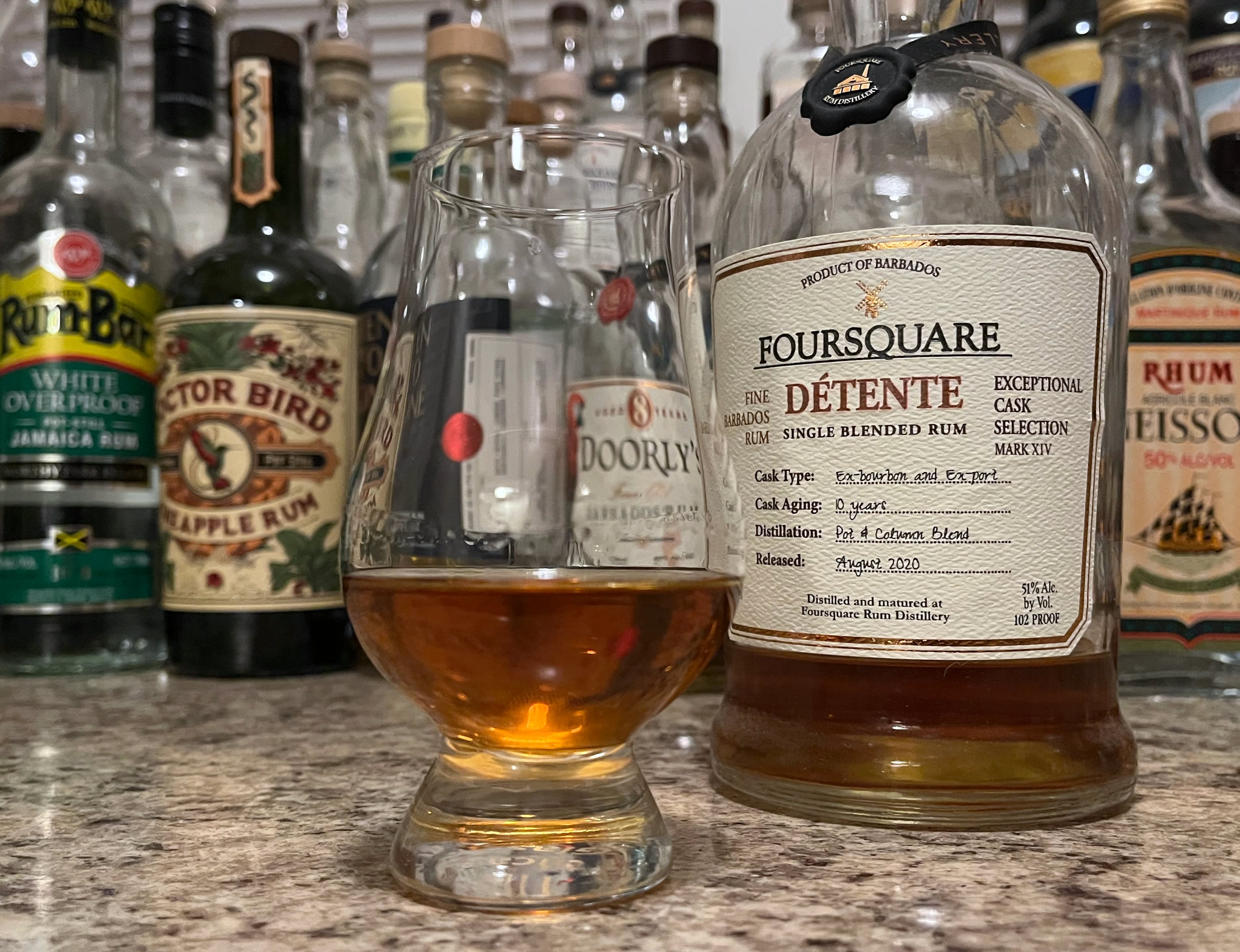 A bottle of Foursquare Détente next to a glencairn of rum on a kitchen counter