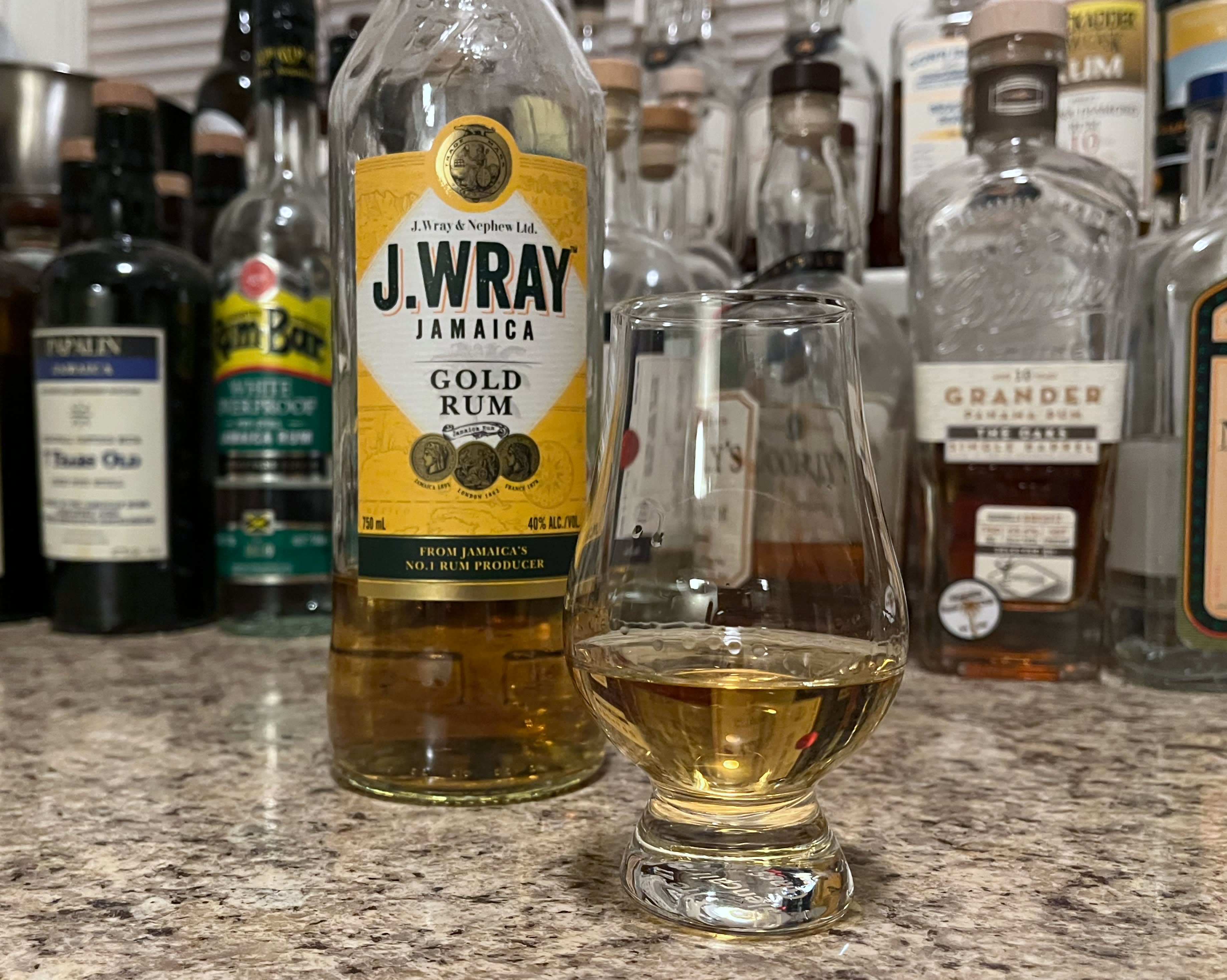 A bottle of J. Wray Gold next to a glencairn of rum