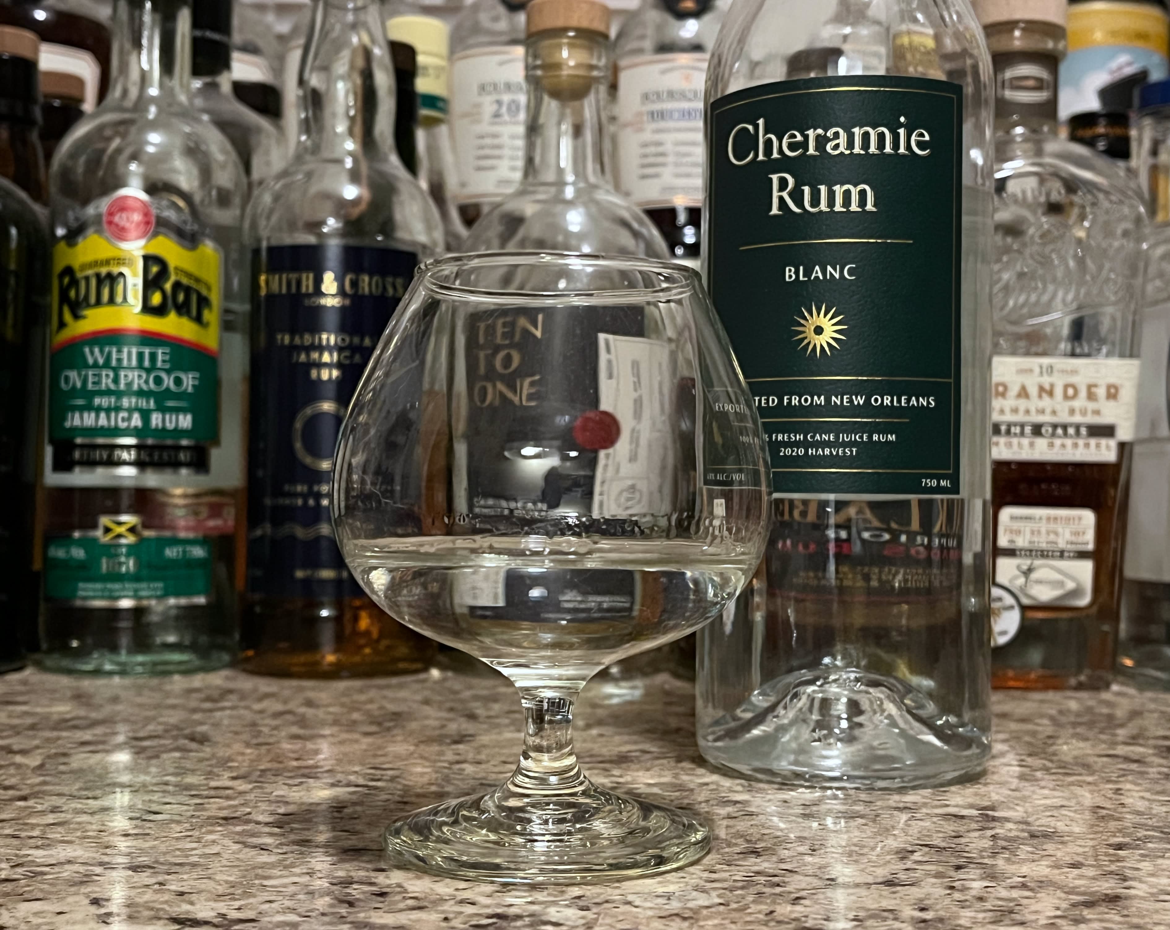 A bottle of Cheramie Blanc next to a glencairn of rum