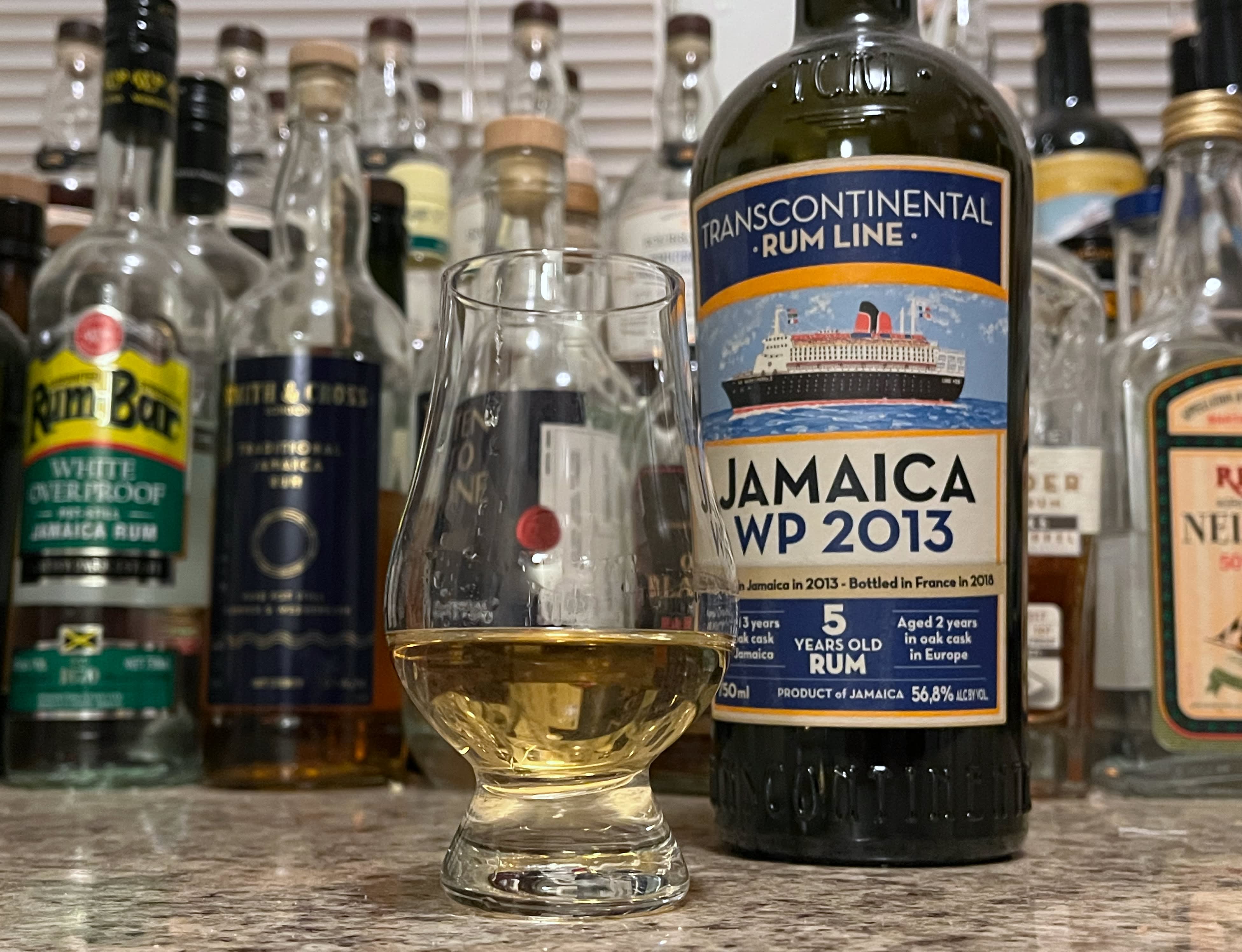 Bottle of TCRL Jamaica WP 2013 sitting next to a rum-filled glencairn