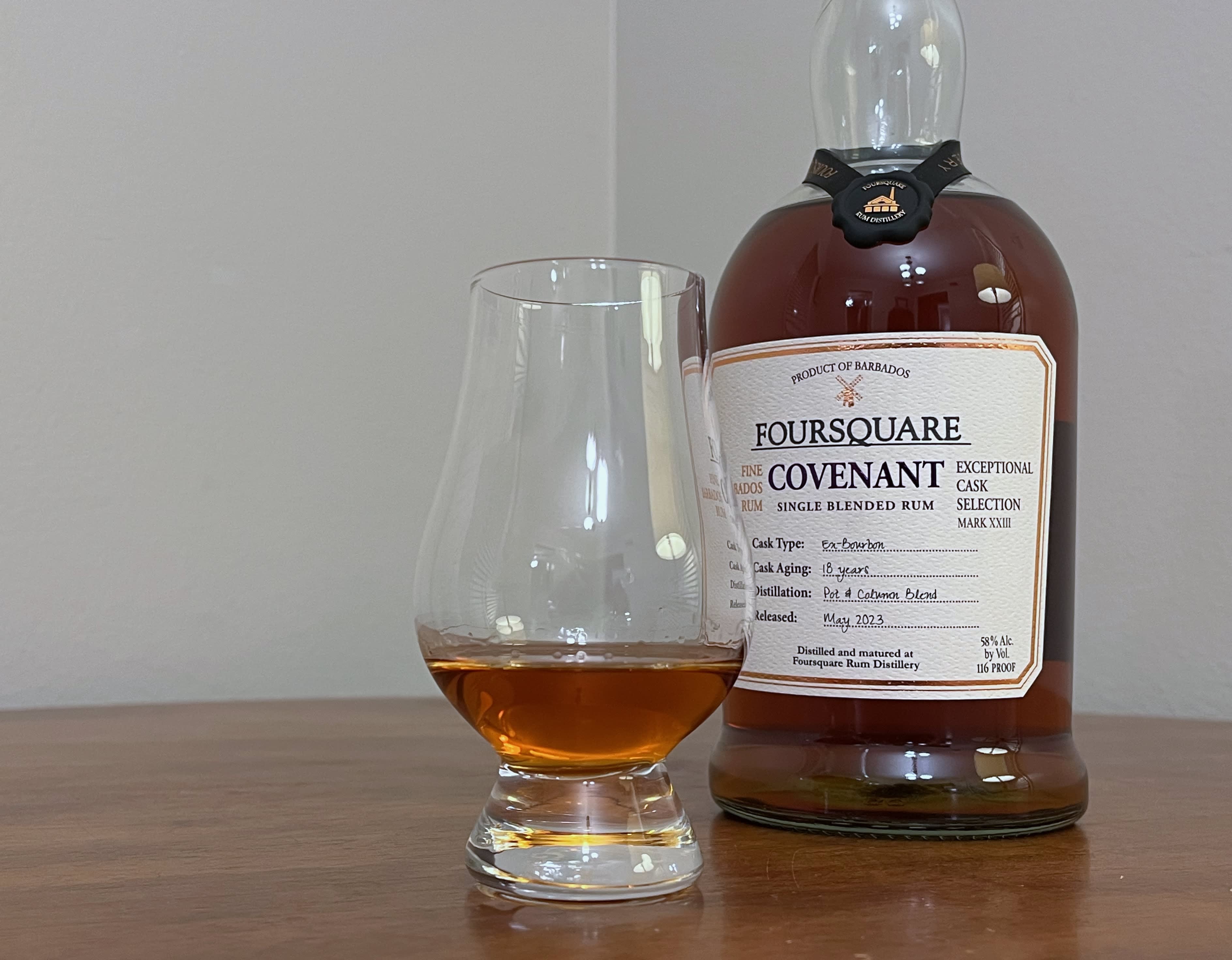 A bottle of Foursquare Covenant next to a glencairn of rum on a tabletop