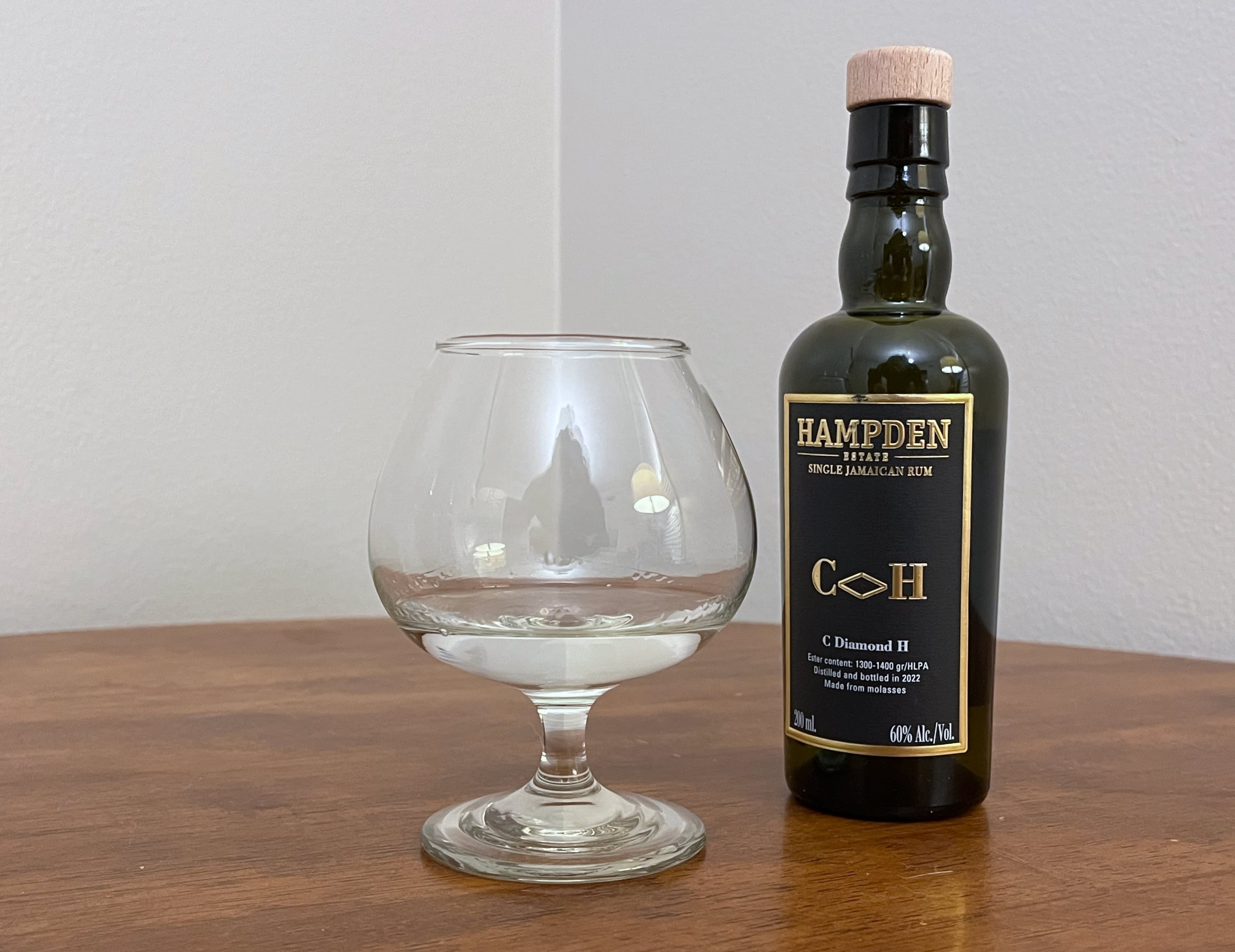 A bottle of Hampden 8 Marks C<>H next to a glass of rum