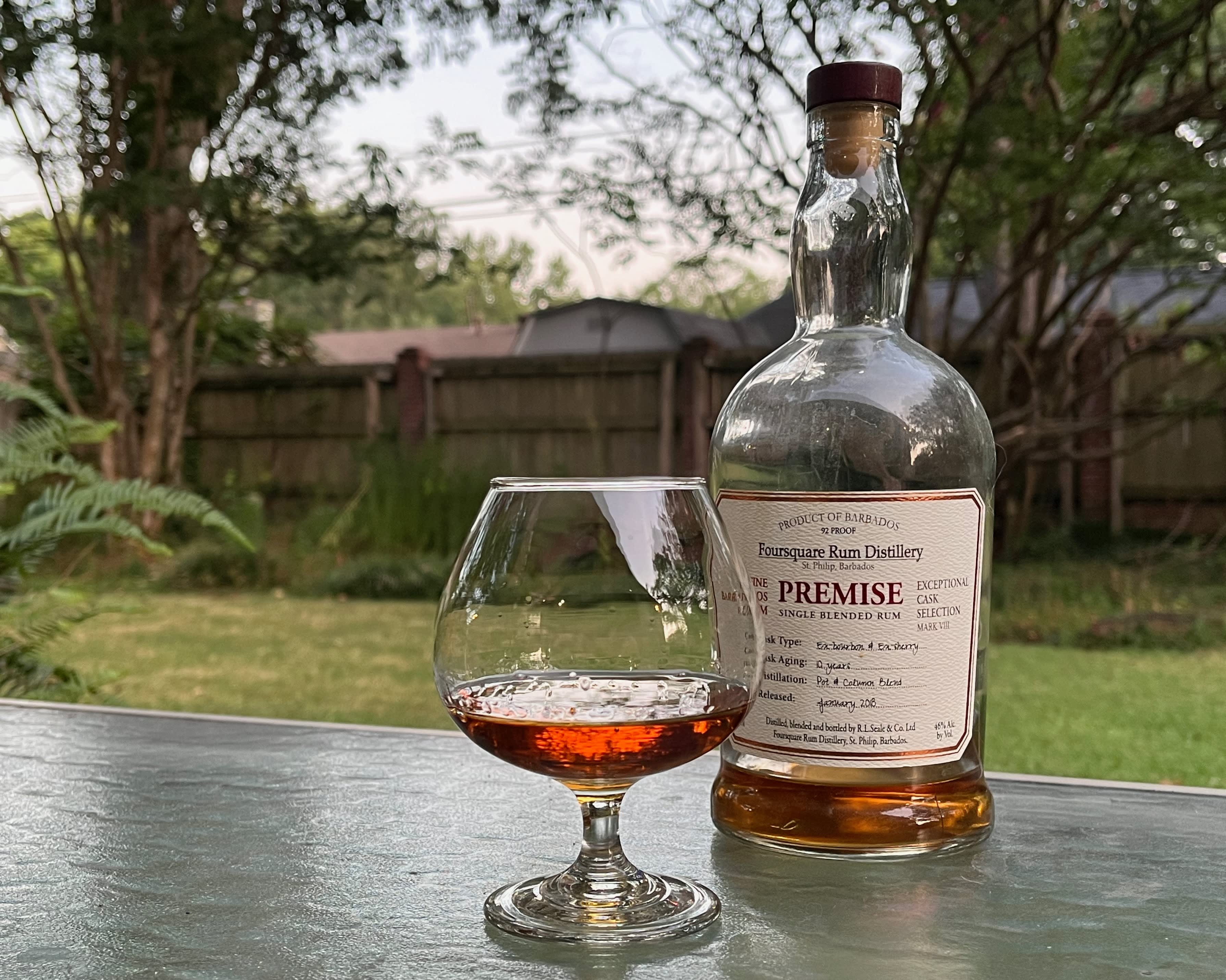 A bottle of Foursquare Premise next to a glass of rum