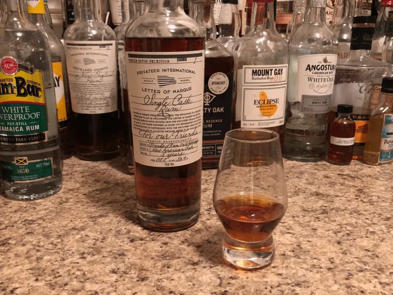 Privateer rum bottle sitting on a kitchen counter, next to a glencairn glass filled a quarter way up with rum