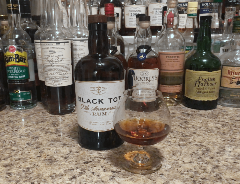 Black Tot rum bottle on a counter next to a snifter with rum poured in it