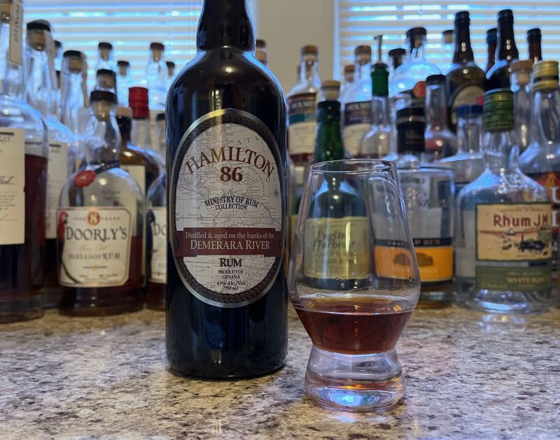 Bottle of Hamilton 86 next to a glass of rum