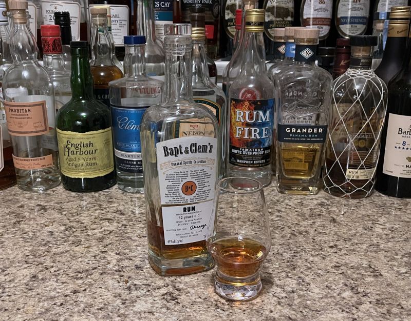 Bapt & Clem's bottle sitting next to a glencairn filled with rum