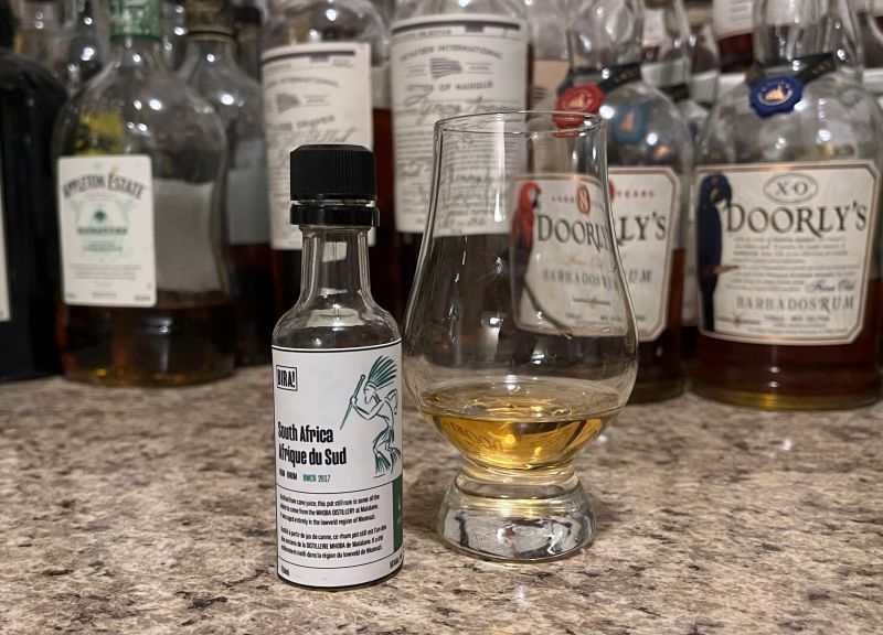 Sample bottle of Bira! South Africa Bourbon Finish on a counter next to a glencairn with rum poured in it