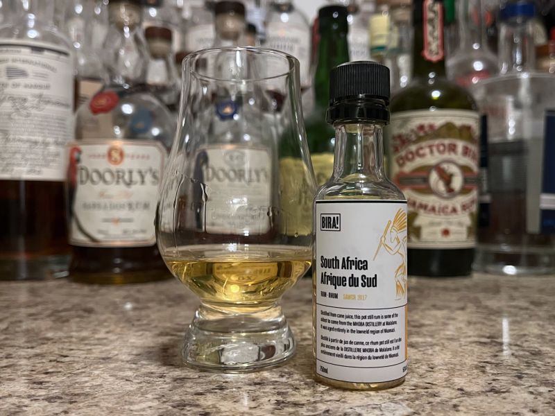 Sample bottle of Bira! South African Whisky Finish on a counter next to a glencairn with rum poured in it