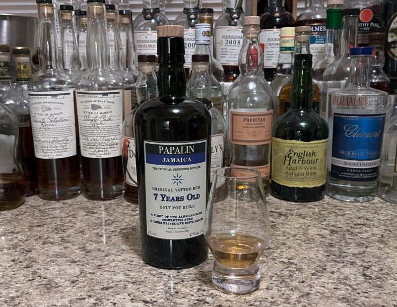 Bottle of Papalin Jamaica on a counter next to a glencairn with rum poured in it