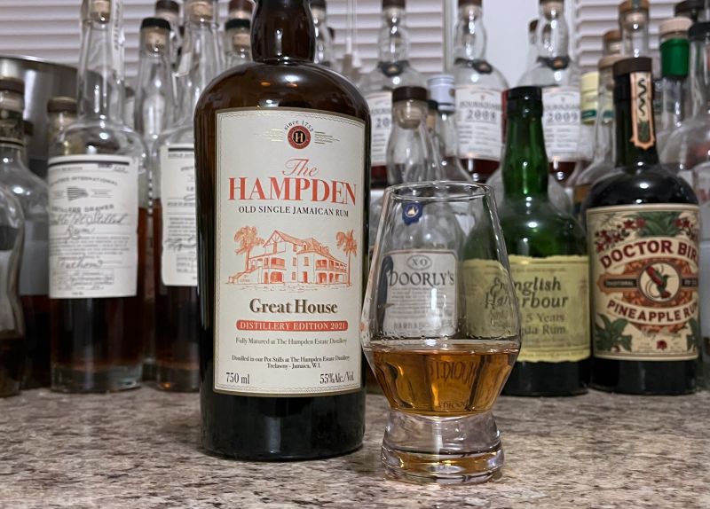 A bottle of Hampden Great House 2021 next to a glencairn of rum on a kitchen counter