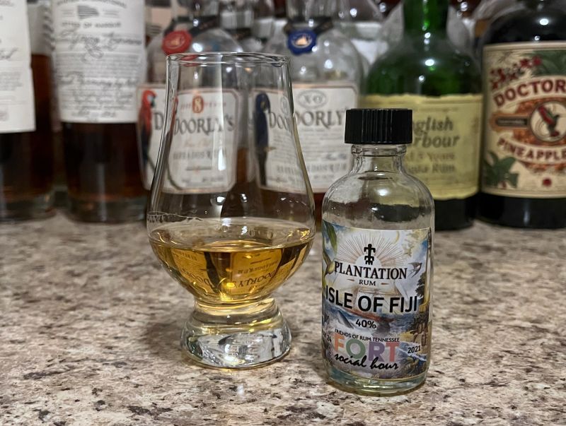 A sample bottle of Plantation Isle of Fiji next to a glencairn of rum on a kitchen counter