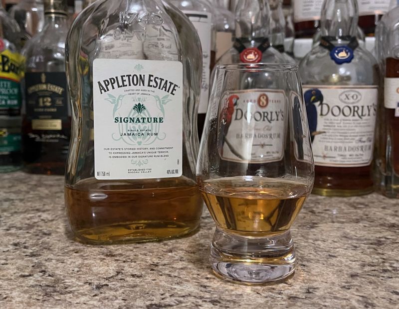 A bottle of Appleton Estate Signature next to a glencairn of rum on a kitchen counter