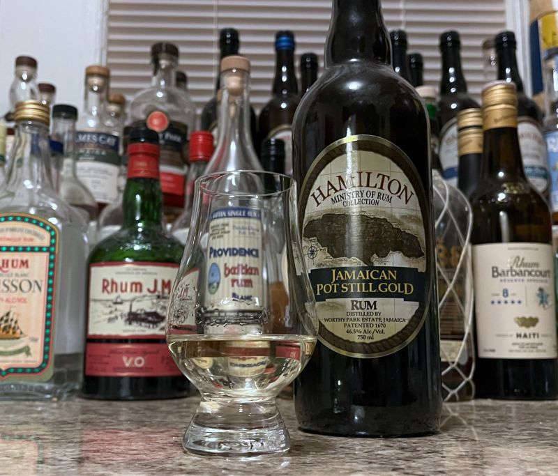 Bottle of Hamilton Pot Still Gold next to a glass of rum